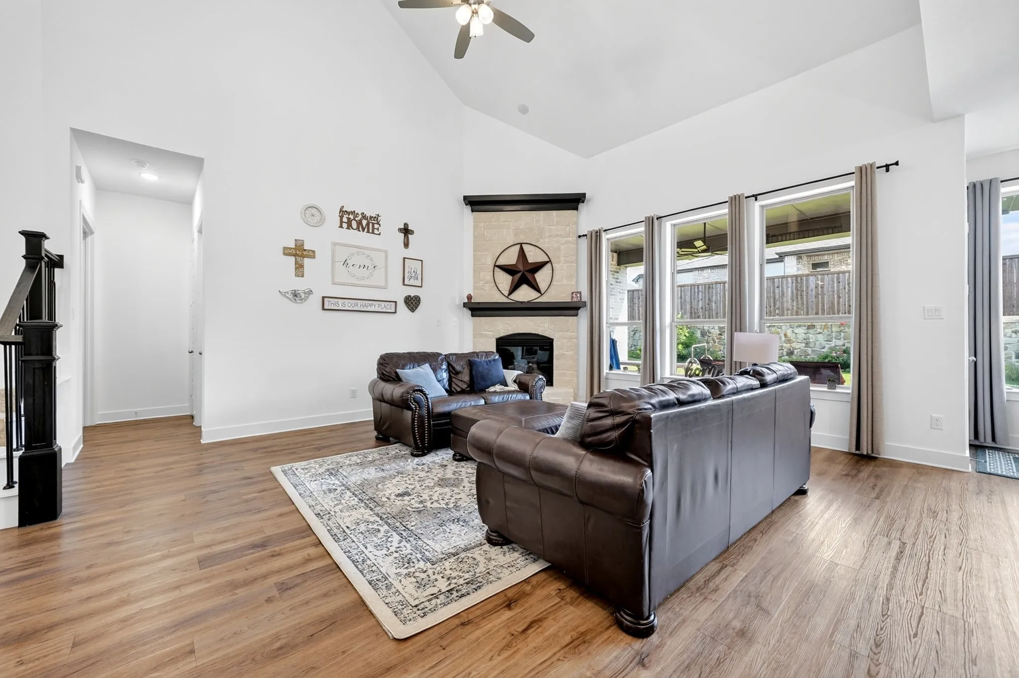 Living area featuring high vaulted ceilings, wood-finish flooring, and a stone-clad fireplace with dark wood mantel