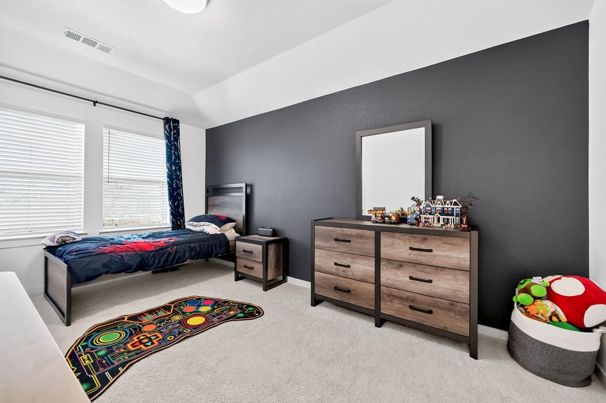 Room featuring two double-hung windows with blinds, a dark accent wall, light-colored carpeting, a ceiling-mounted light fixture, and a built-in air vent