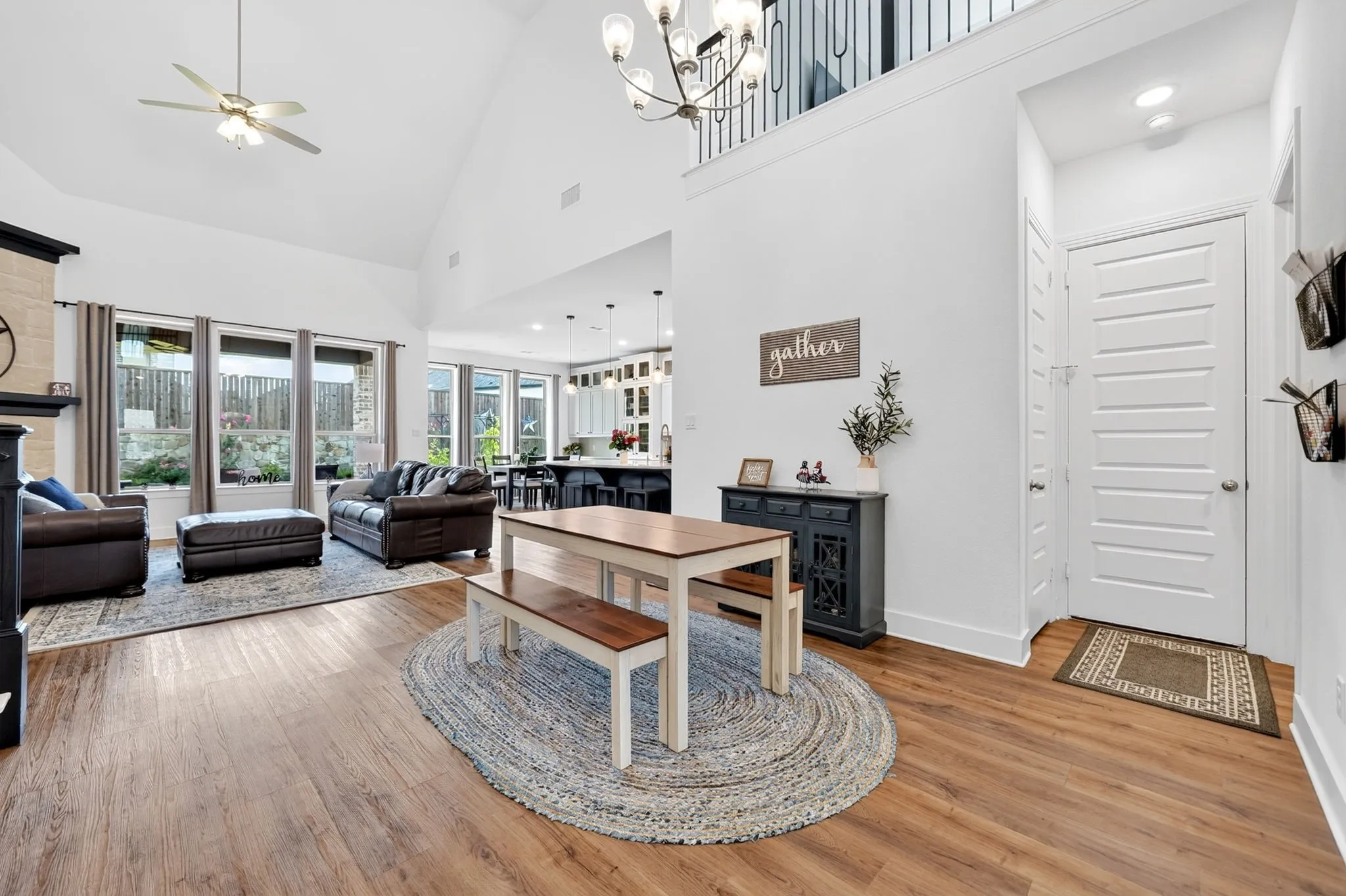 Open-concept living area featuring high vaulted ceilings, wood-finish flooring, and a contemporary chandelier