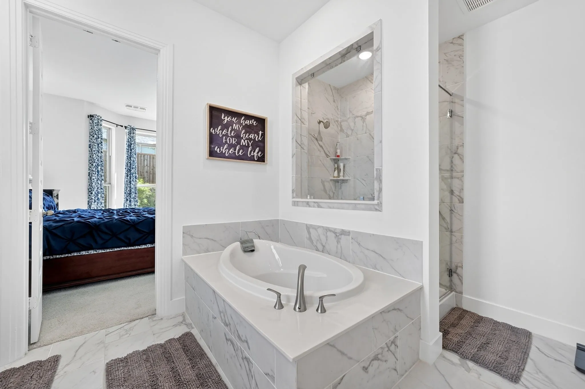 Bathroom featuring a built-in soaking tub with brushed nickel fixtures, a walk-in shower with glass enclosure, white walls, and marble-look tile flooring