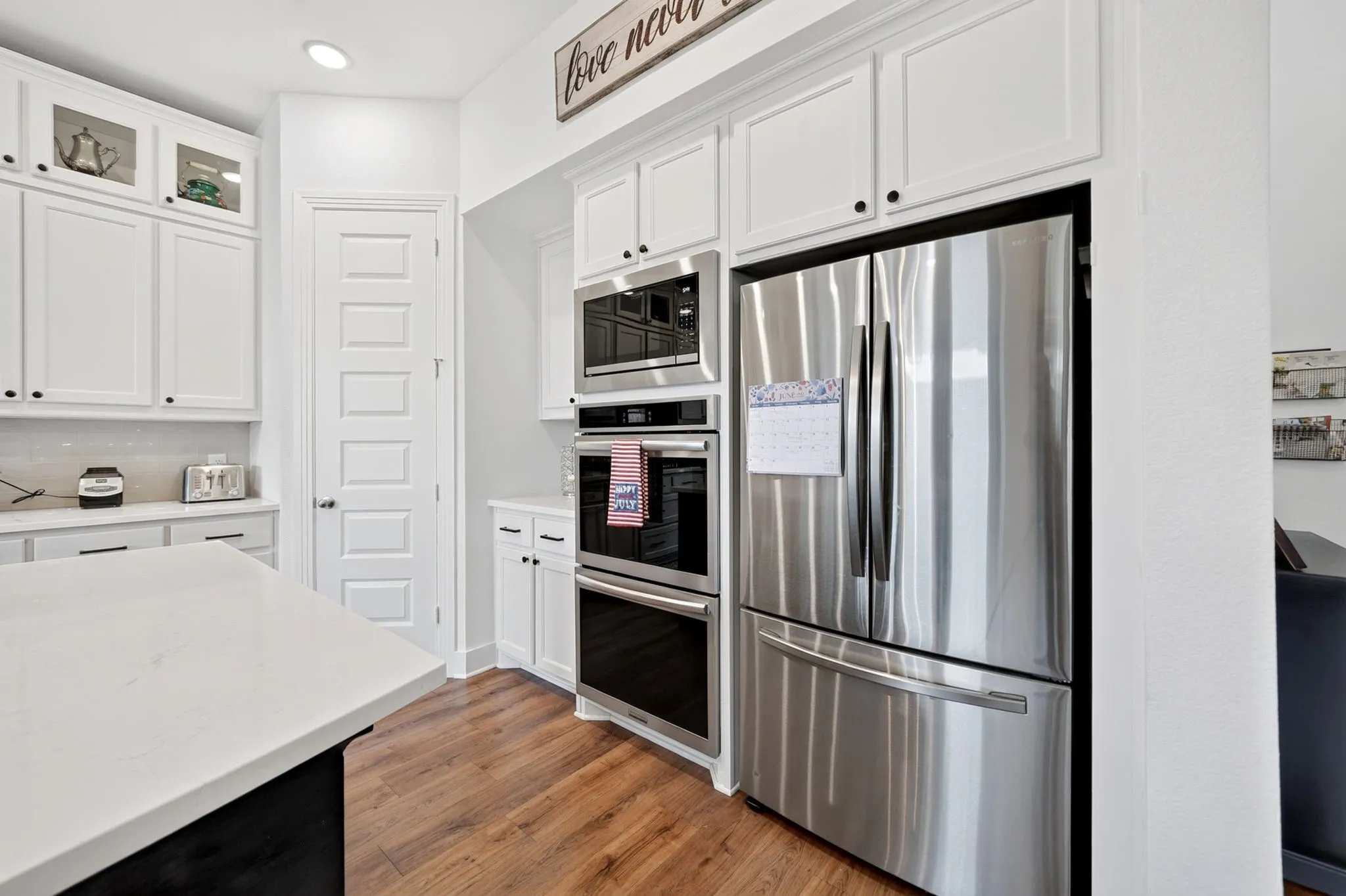 Modern kitchen featuring stainless steel appliances including a built-in microwave, double oven, and refrigerator