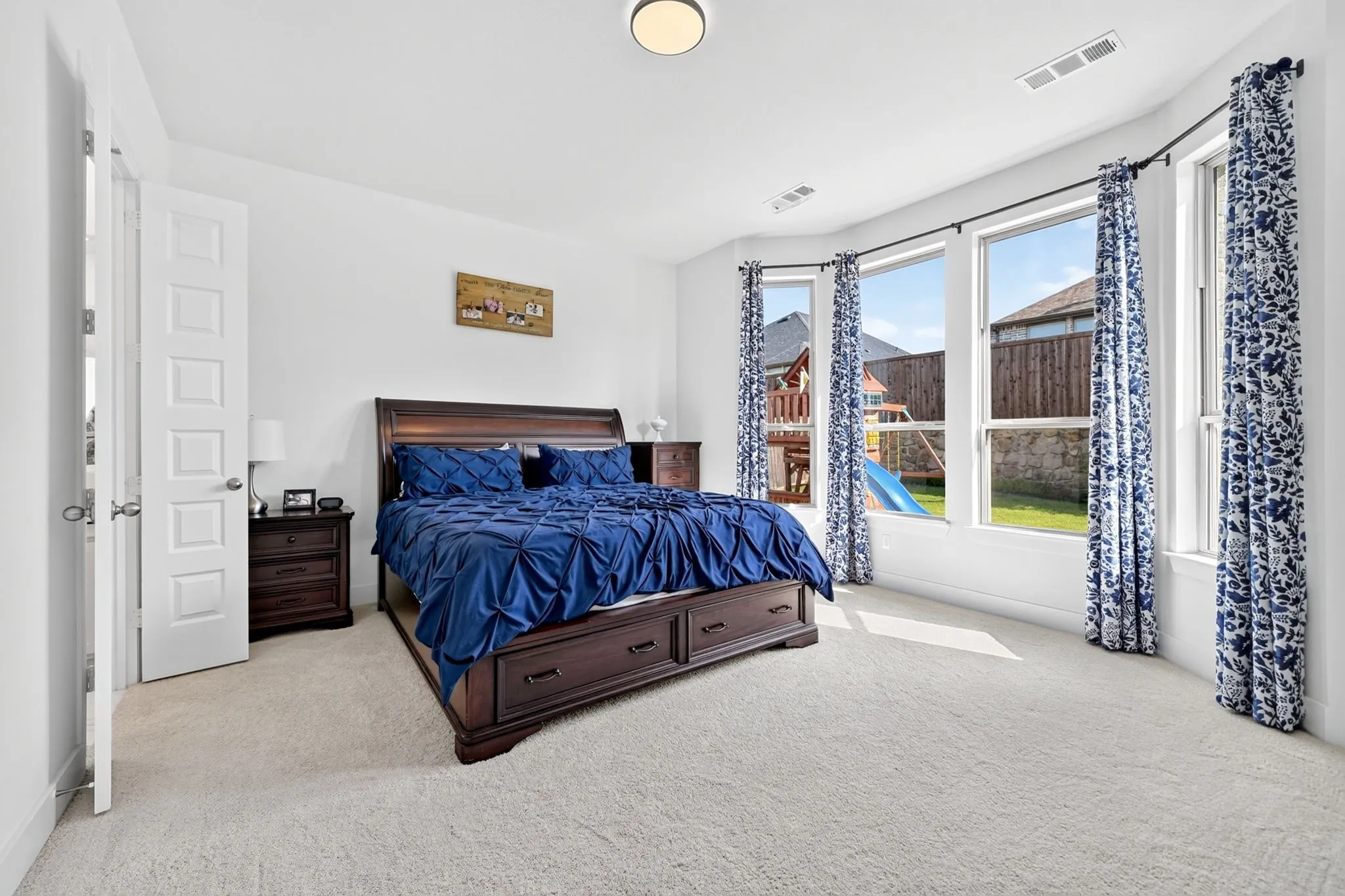 Spacious room featuring light-colored carpeting, a curved wall with multiple windows, and a flush-mount ceiling light fixture