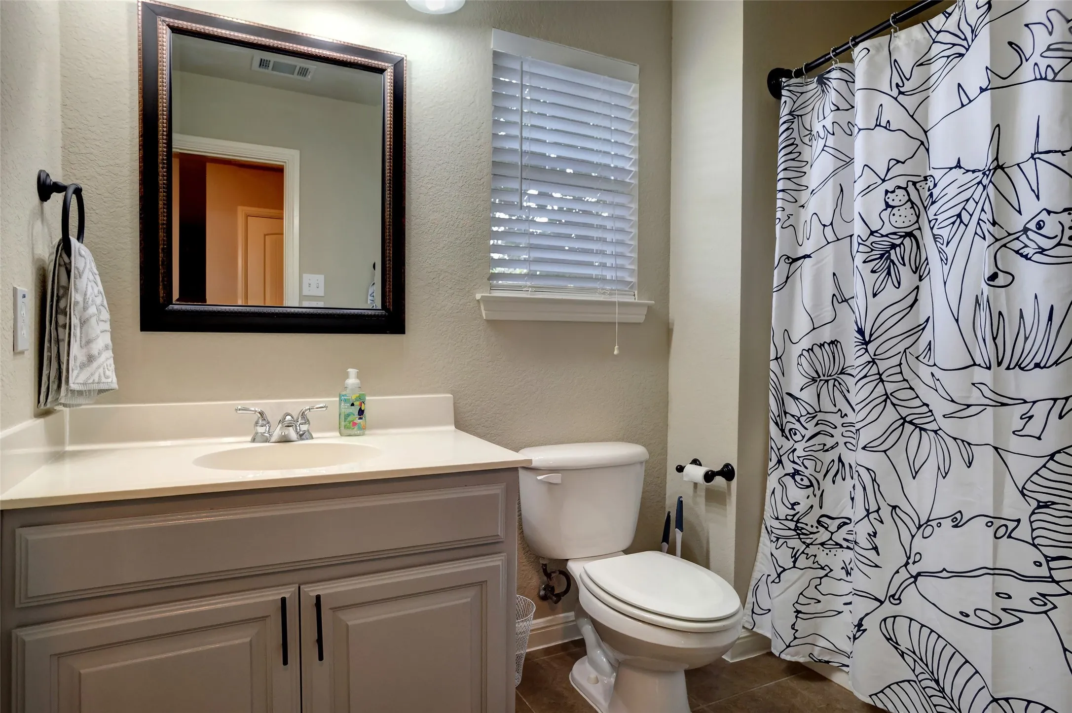 Bathroom vanity featuring a light-toned countertop, undermount sink, and a framed mirror