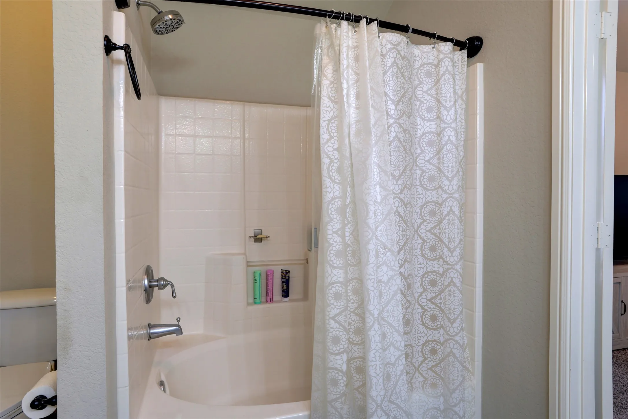 Built-in bathtub and shower combination with white subway tile surround, chrome fixtures, and integrated shower niche