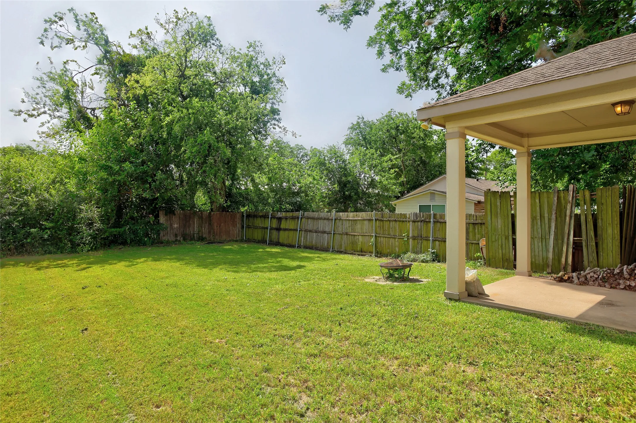 Expansive backyard featuring a manicured lawn, established perimeter fencing, and mature trees providing natural screening