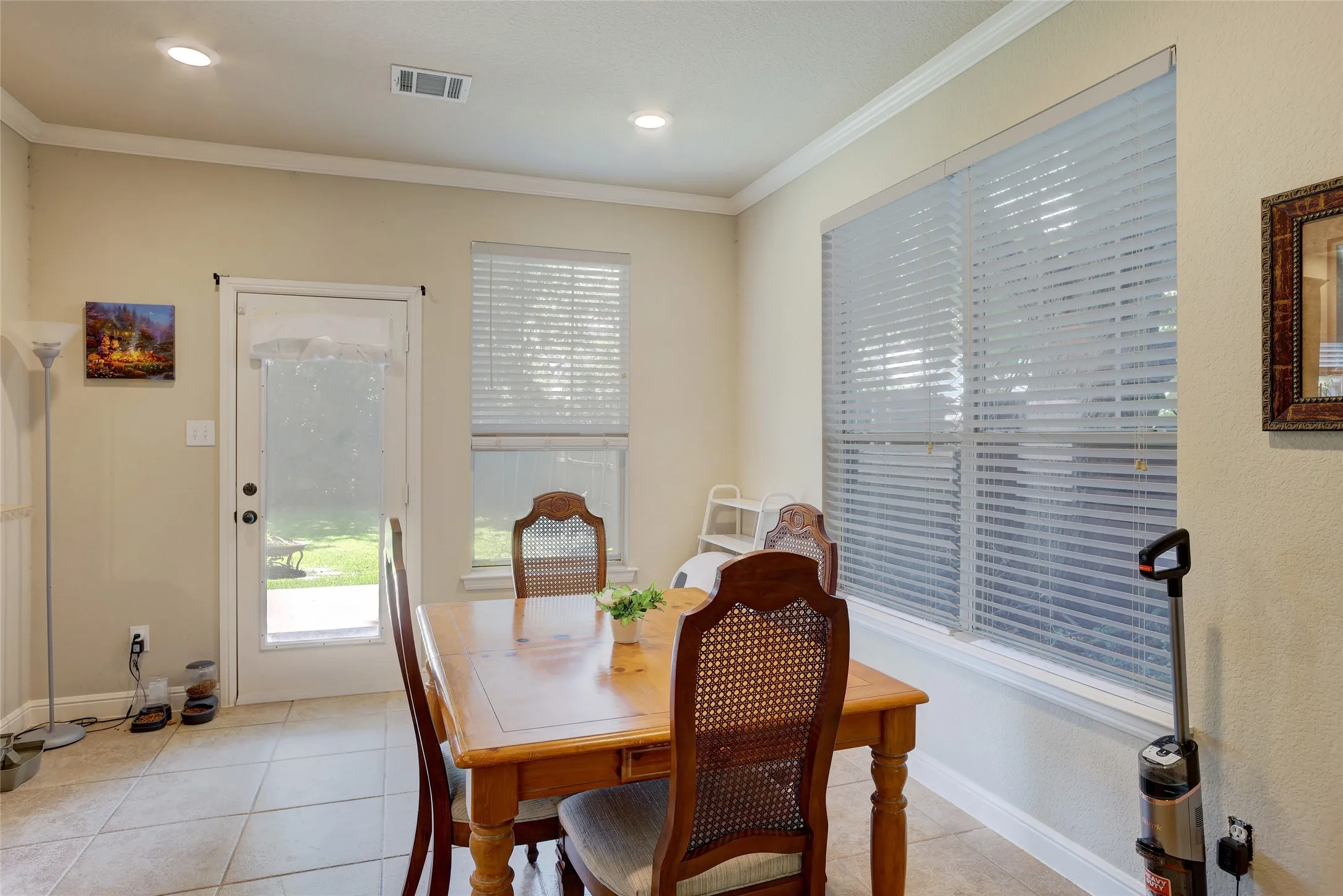 Dining area featuring tile flooring, recessed lighting, crown molding, a full-light door, and a large window with blinds