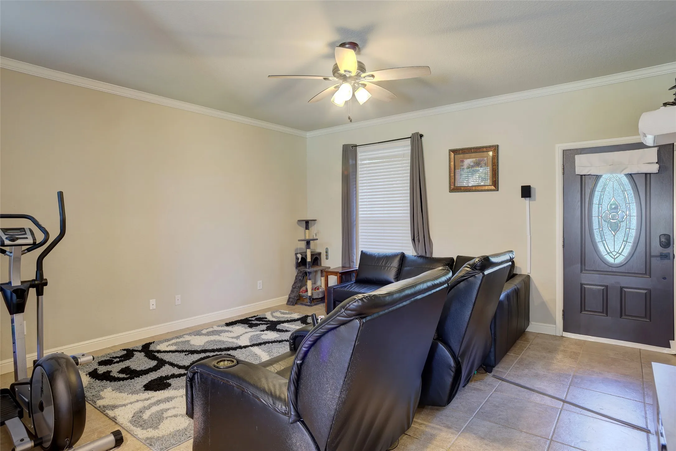 Living area featuring a ceiling fan with integrated lighting, crown molding, and neutral wall tones