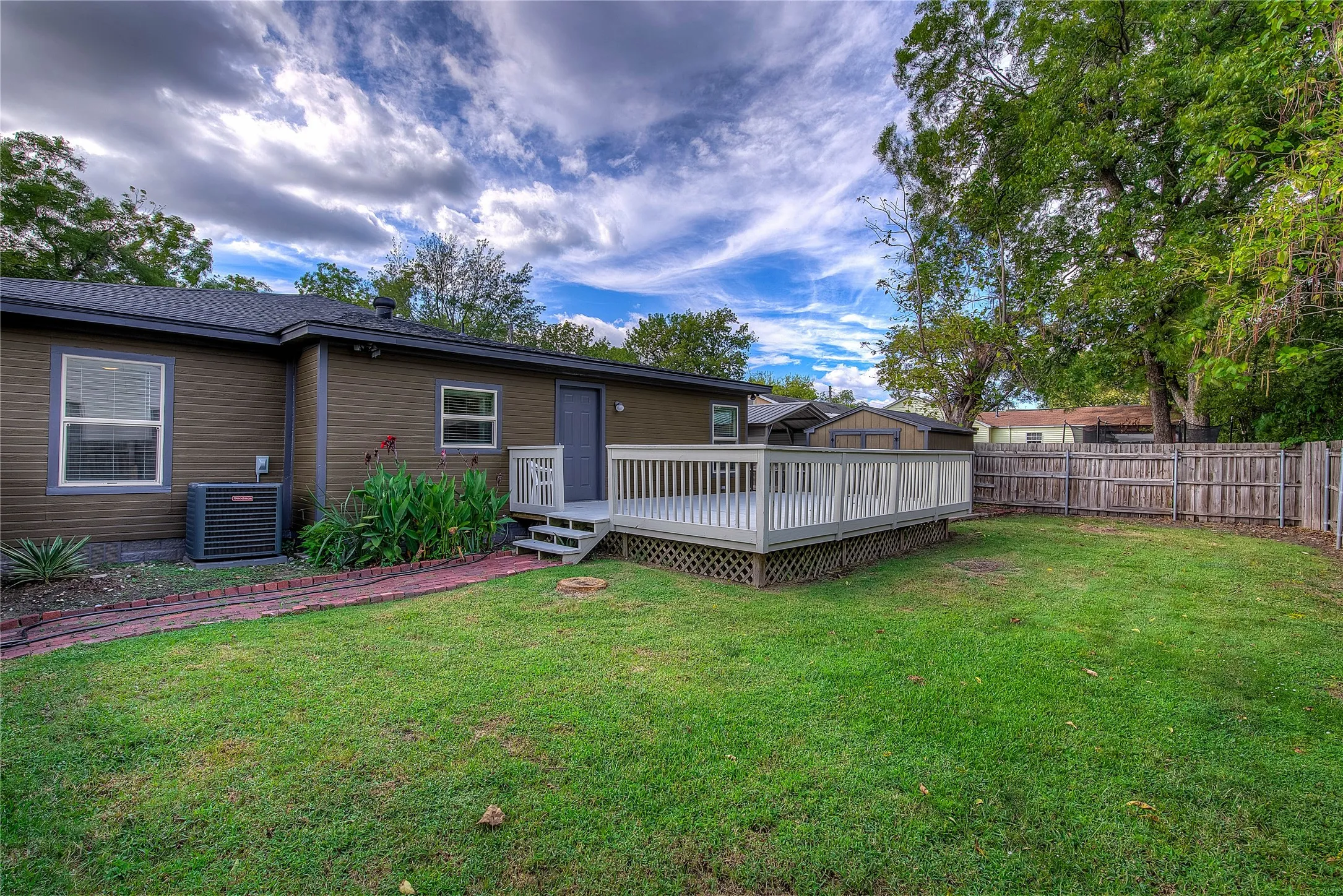 Back yard view showing landscaping, privacy fence and wood deck.