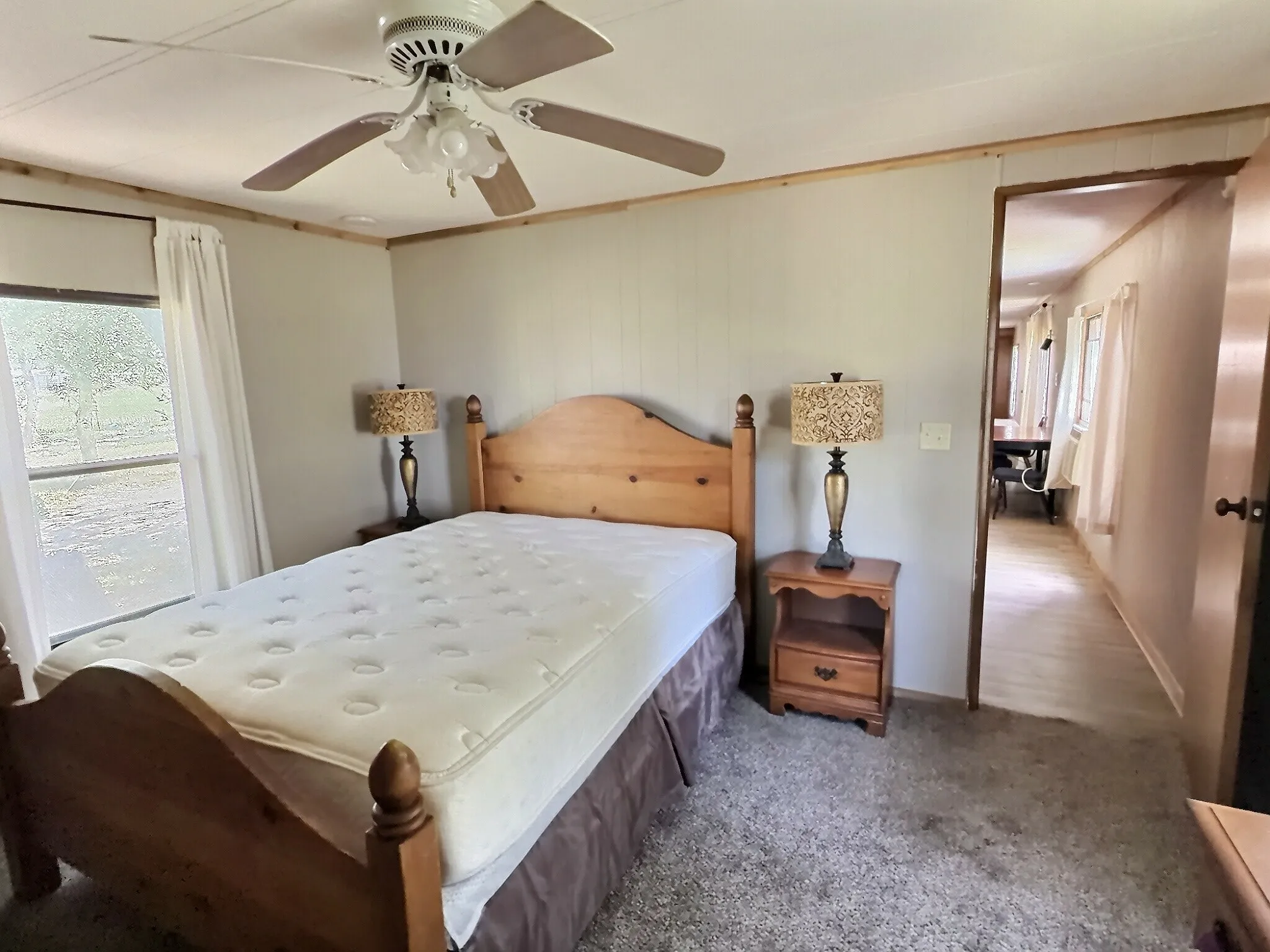 Carpeted bedroom featuring a ceiling fan, a window with exterior views