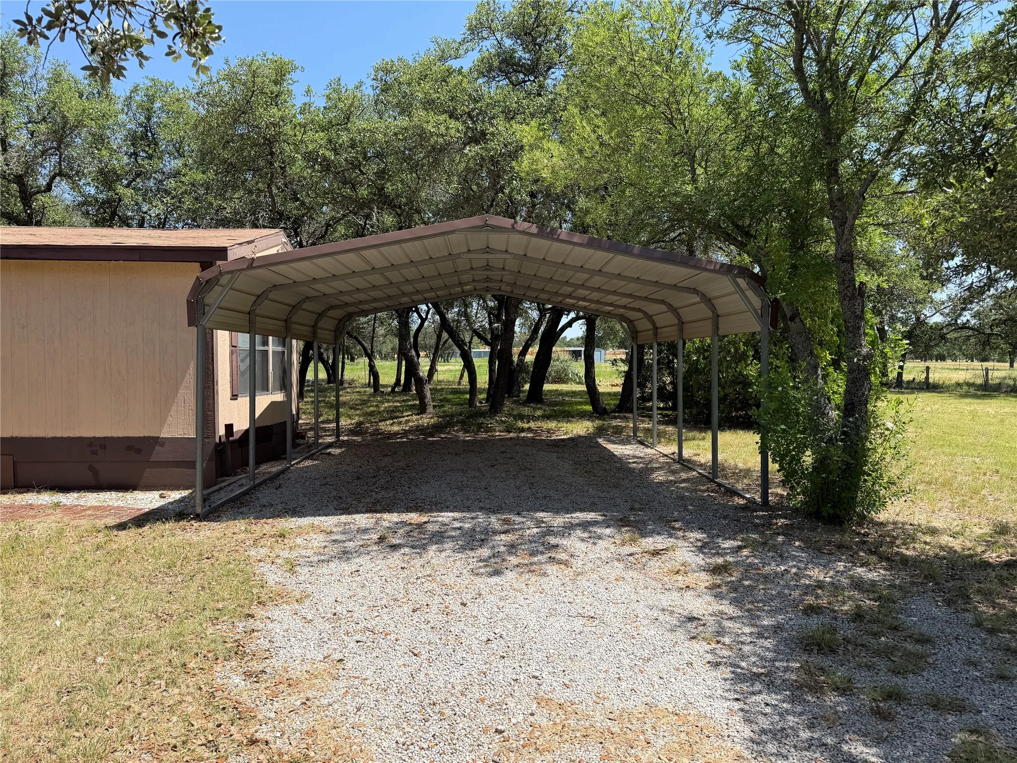 Expansive covered carport with gravel driveway