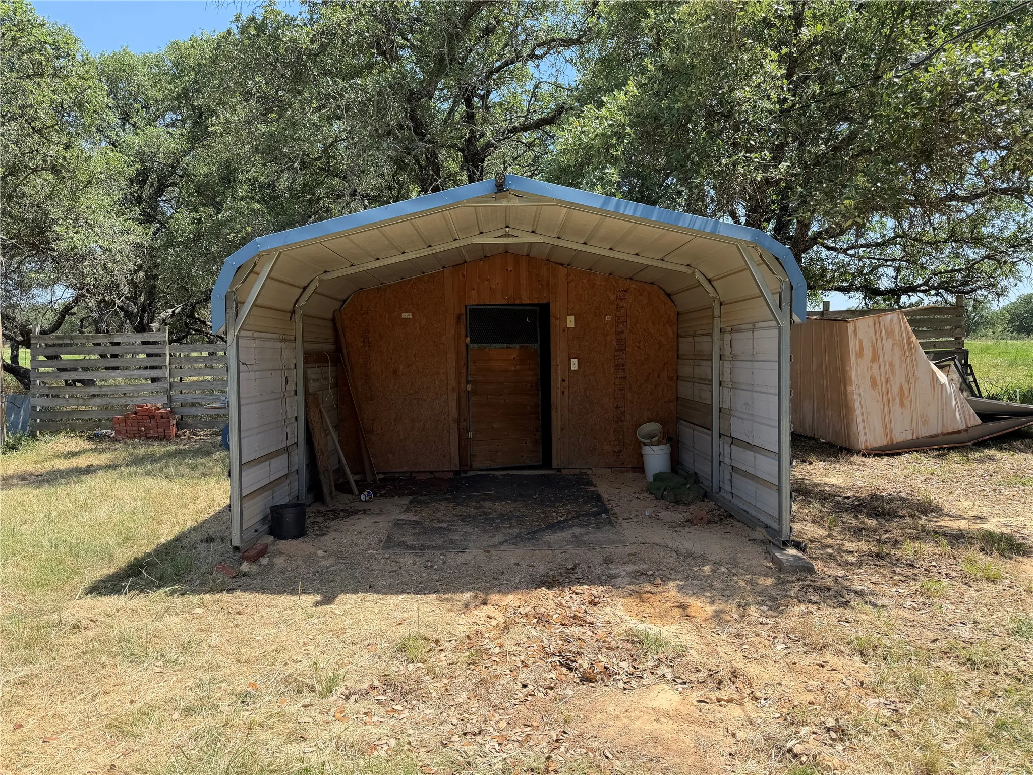 Metal carport structure featuring a light blue roof and corrugated metal siding with added storage