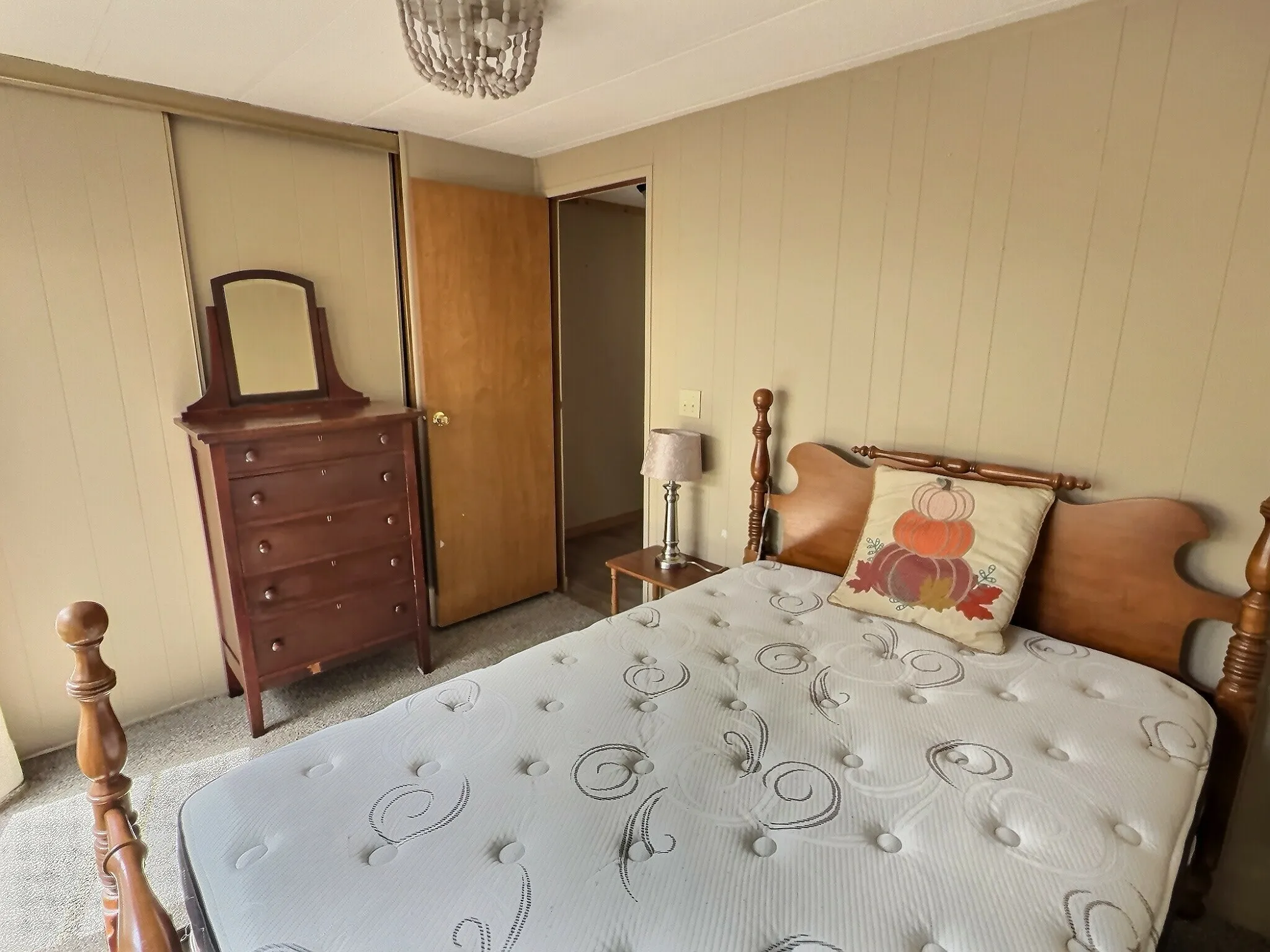 Bedroom featuring light-colored carpeting, a wood-finish door, and a decorative ceiling light fixture