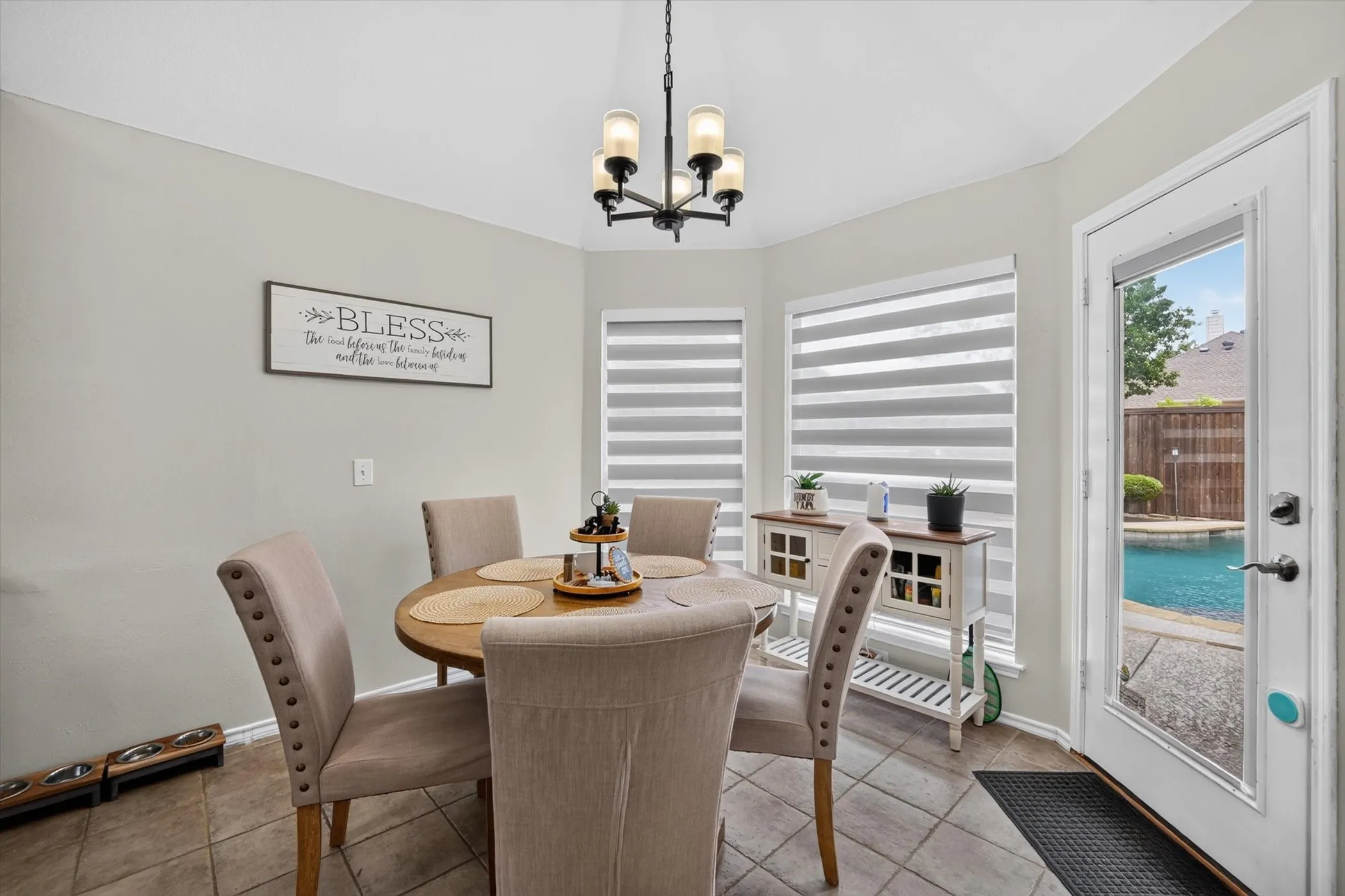 Dining area featuring tile flooring, a multi-light chandelier, and bay windows with horizontal blinds