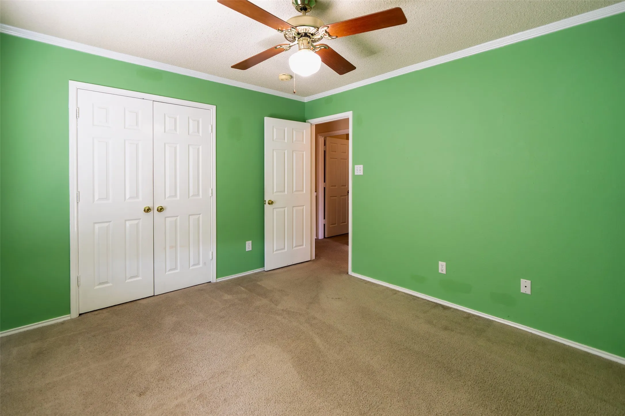 Generously sized secondary bedroom with crown molding, ceiling fan and walk-in closet