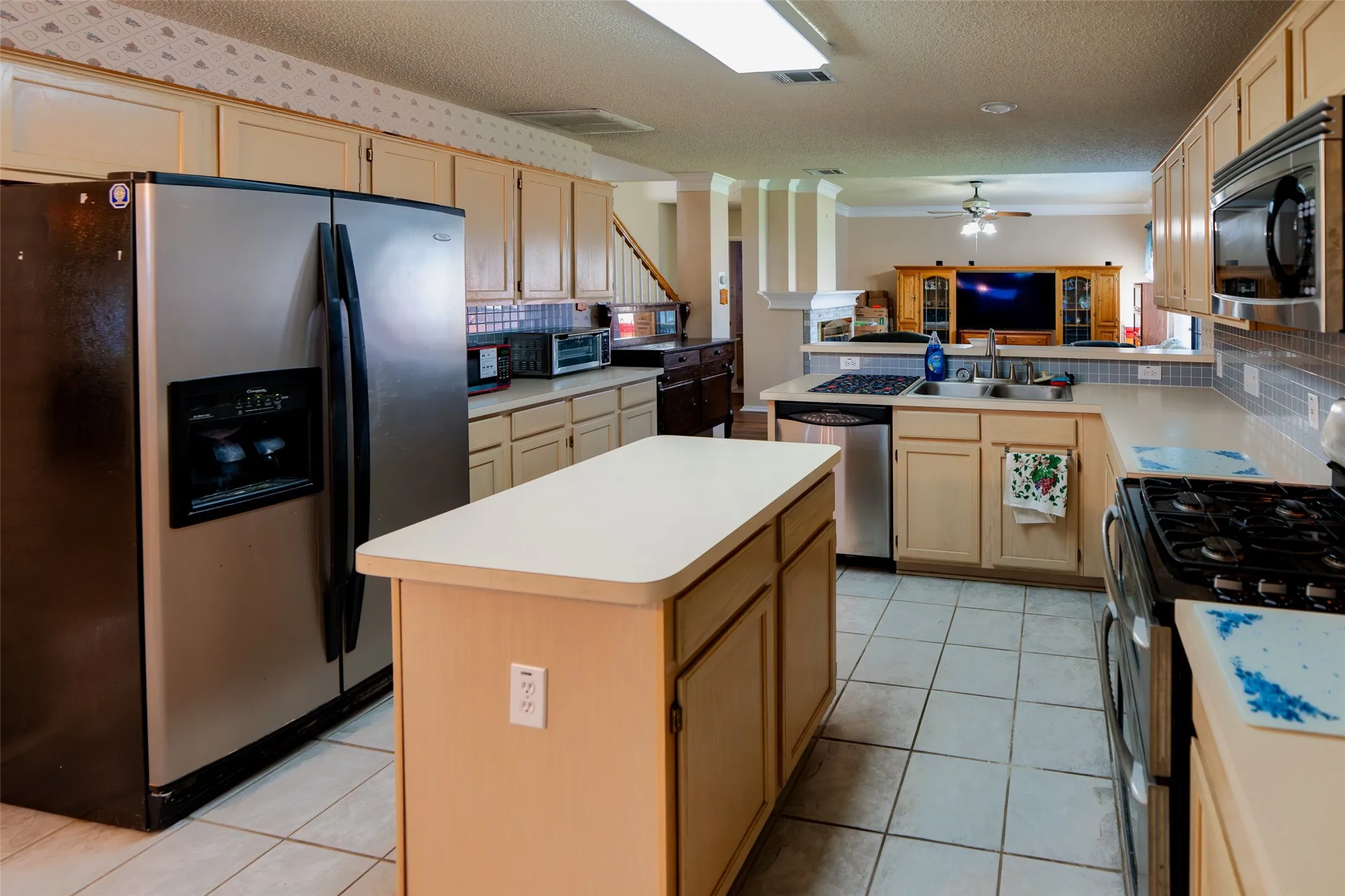 Spacious kitchen features a center island, breakfast bar, gas range, and refrigerator that will convey with the home