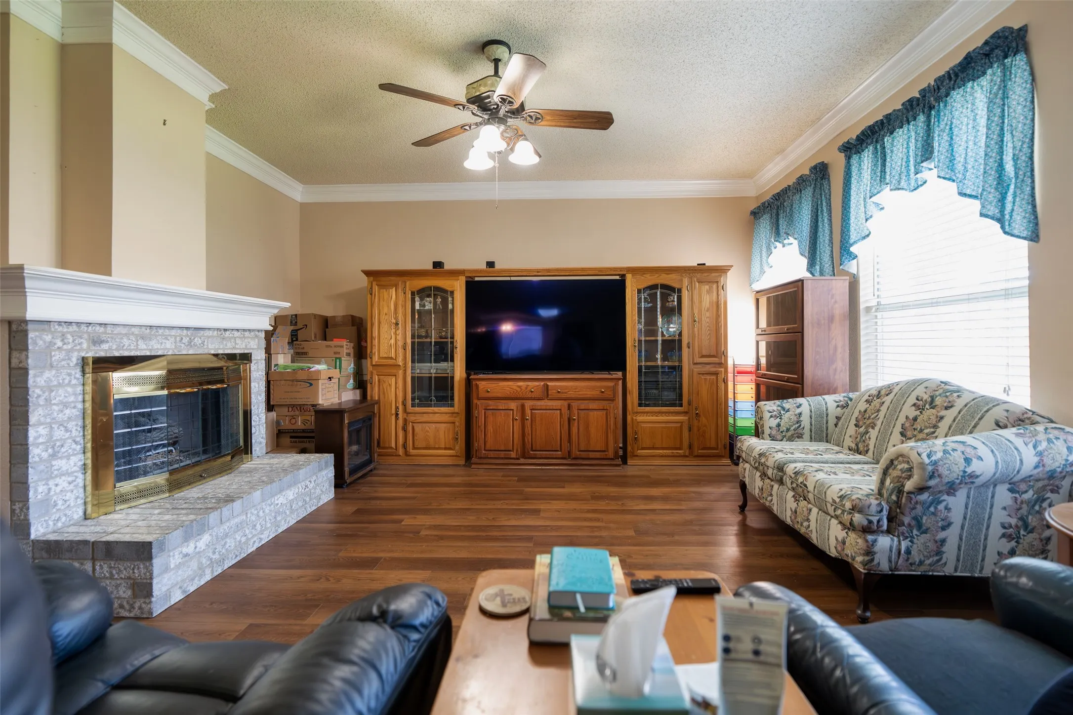 Warm and inviting Family Room anchored by a floor-to-ceiling fireplace with soaring ceilings and oversized windows
