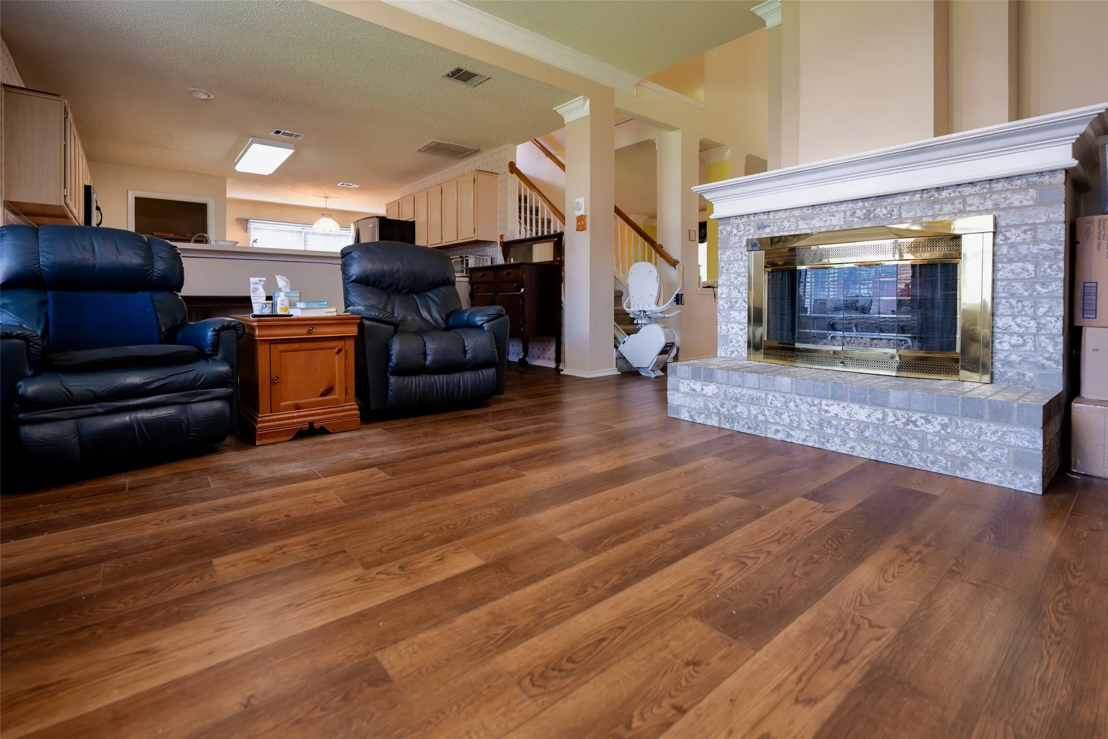 Family Room features a striking brick fireplace and an open layout overlooking the kitchen, creating the heart of the home