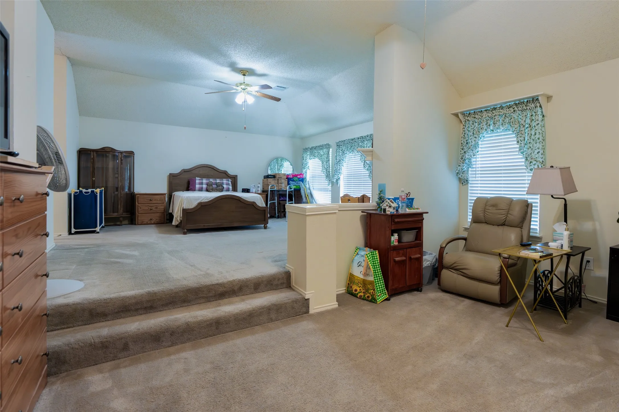 Expansive primary suite featuring a raised bedroom overlooking the private sitting area