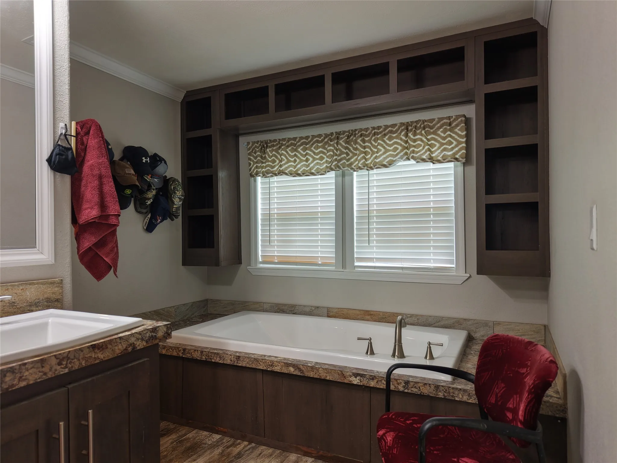 Soaking tub with deck-mounted fixtures, framed by a window with blinds and valance