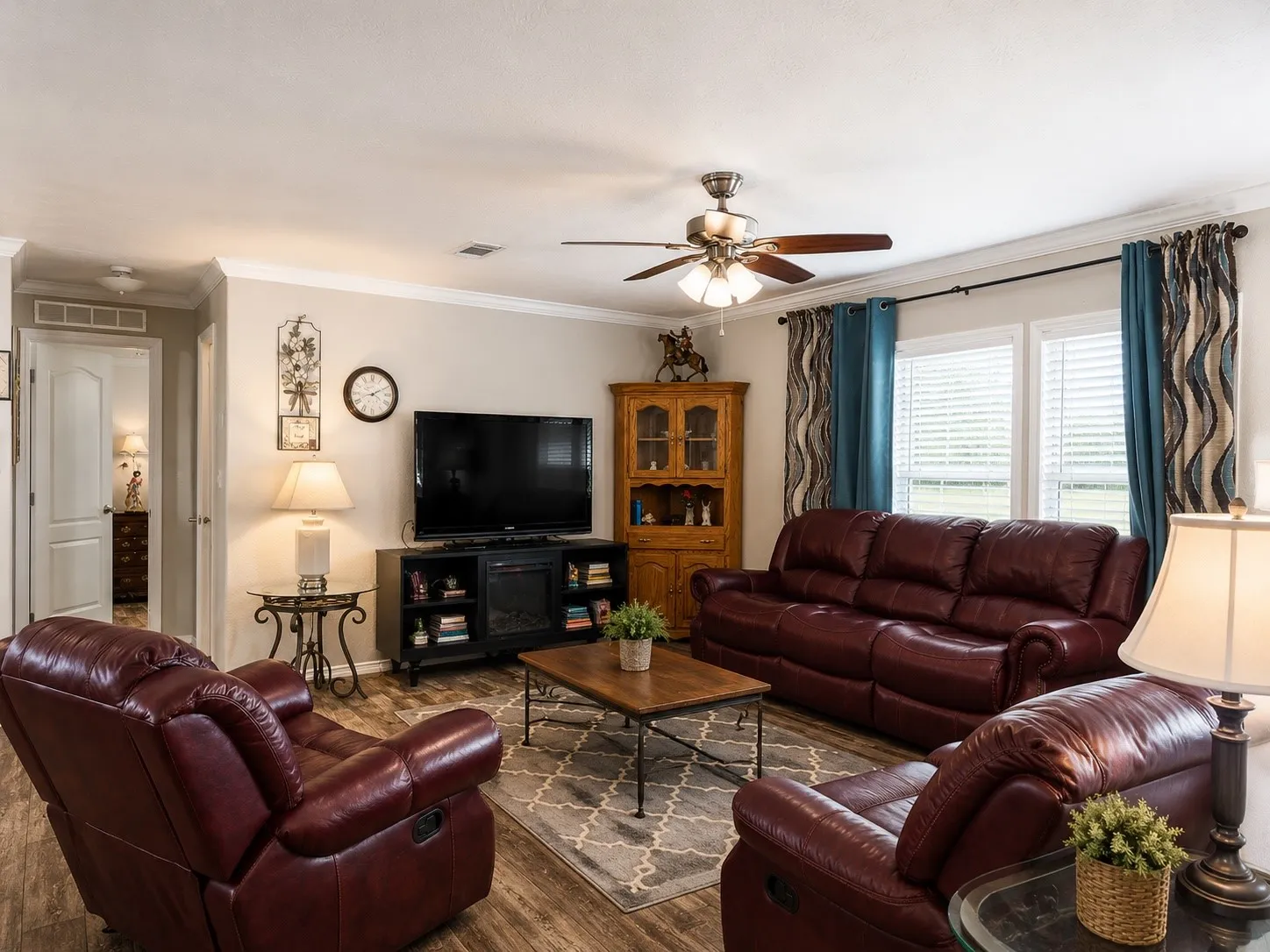 Spacious living area featuring wood-finish flooring, crown molding, and large windows