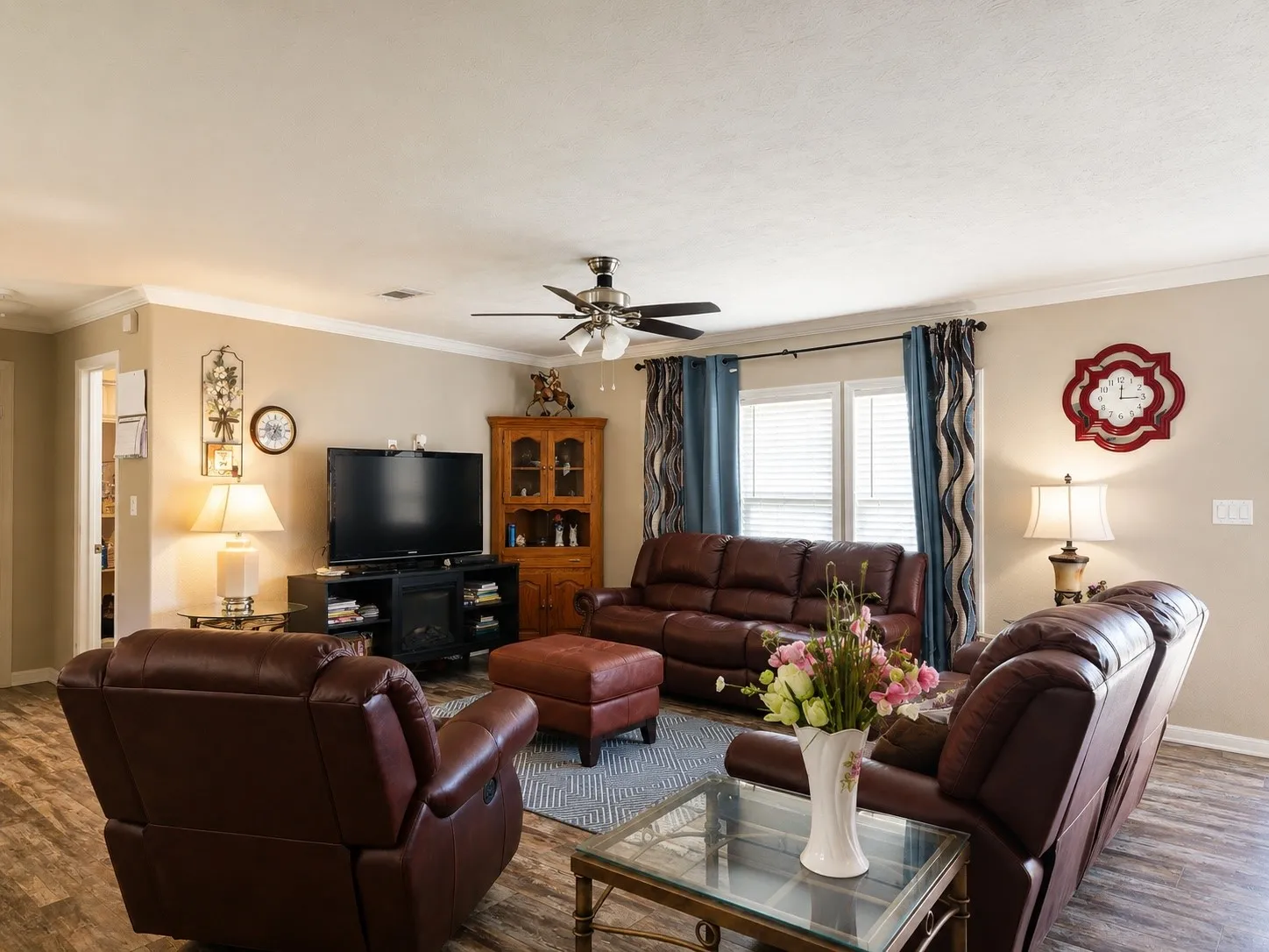 Living area featuring wood-finish flooring, a ceiling fan, crown molding, and neutral wall tones