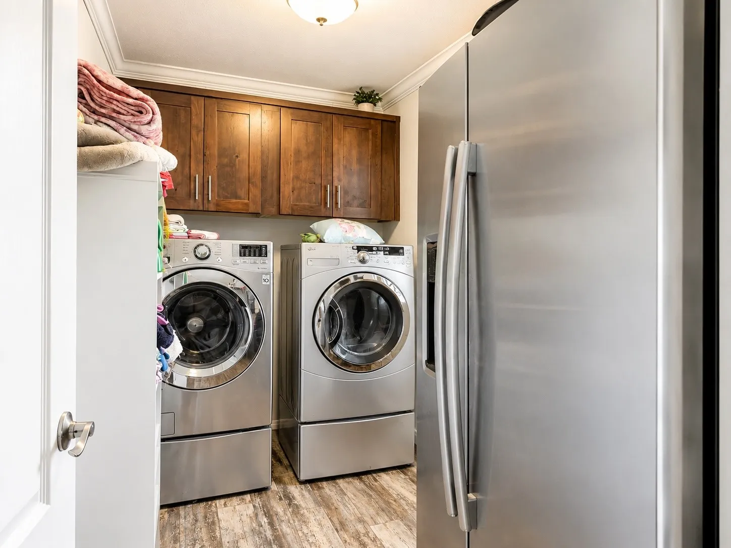 Laundry area featuring wood-finish flooring, crown molding, and built-in wood cabinetry
