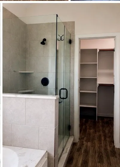Glass-enclosed shower with tiled walls and built-in shelving