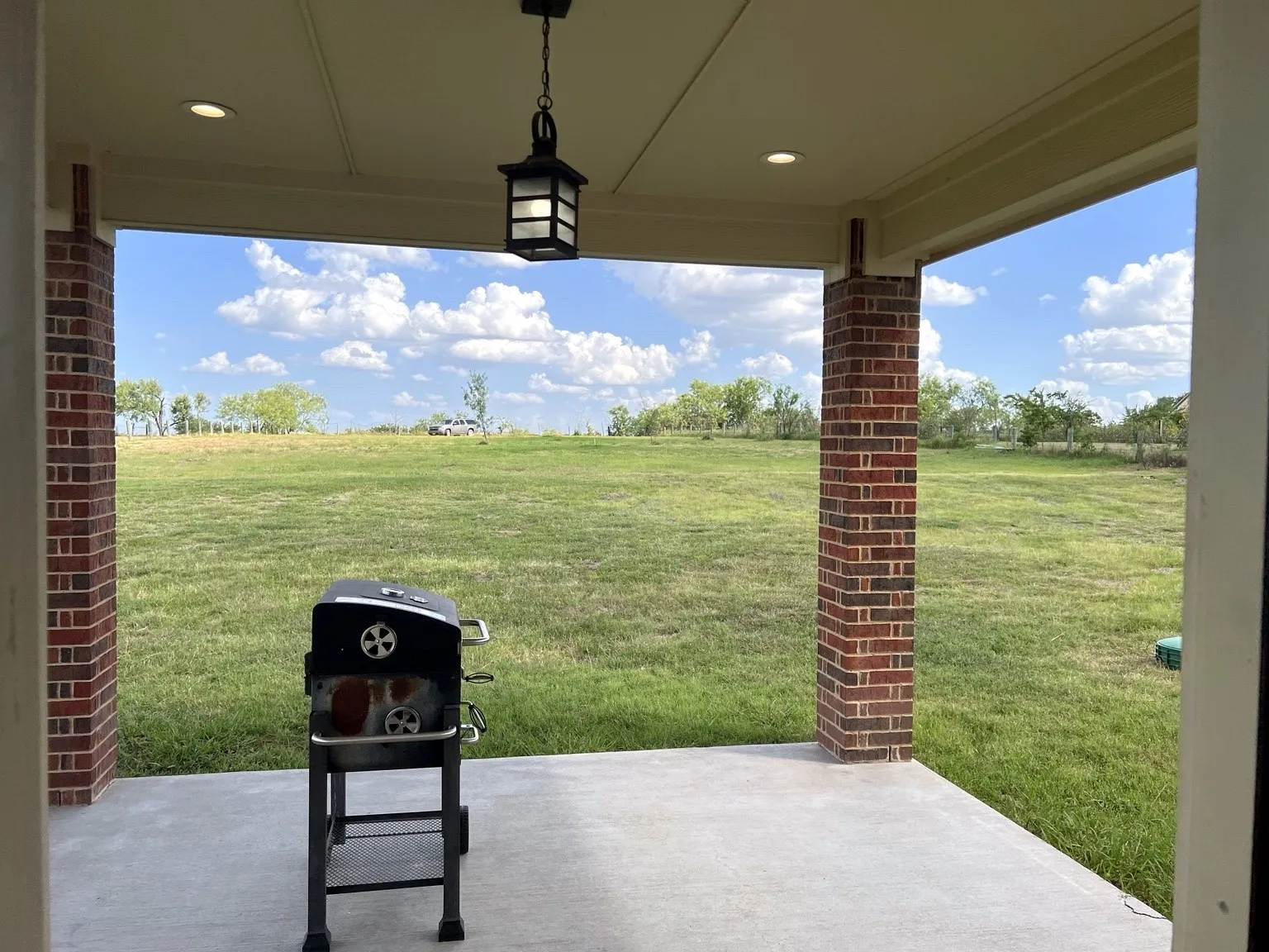 Covered patio with a concrete slab, brick columns, and recessed lighting