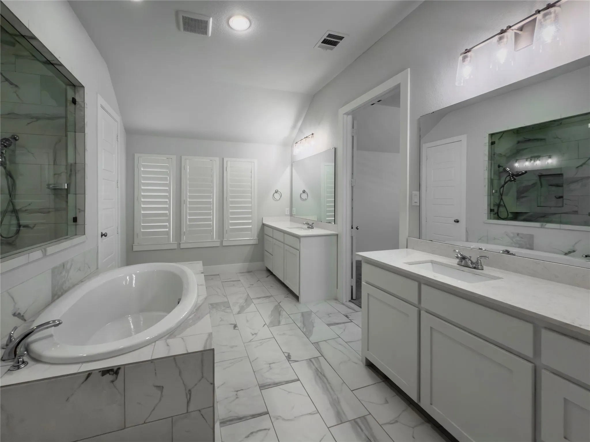 Freestanding soaking tub with surrounding tilework, dual vanity sinks with quartz countertops, and a glass-enclosed shower with tiled walls