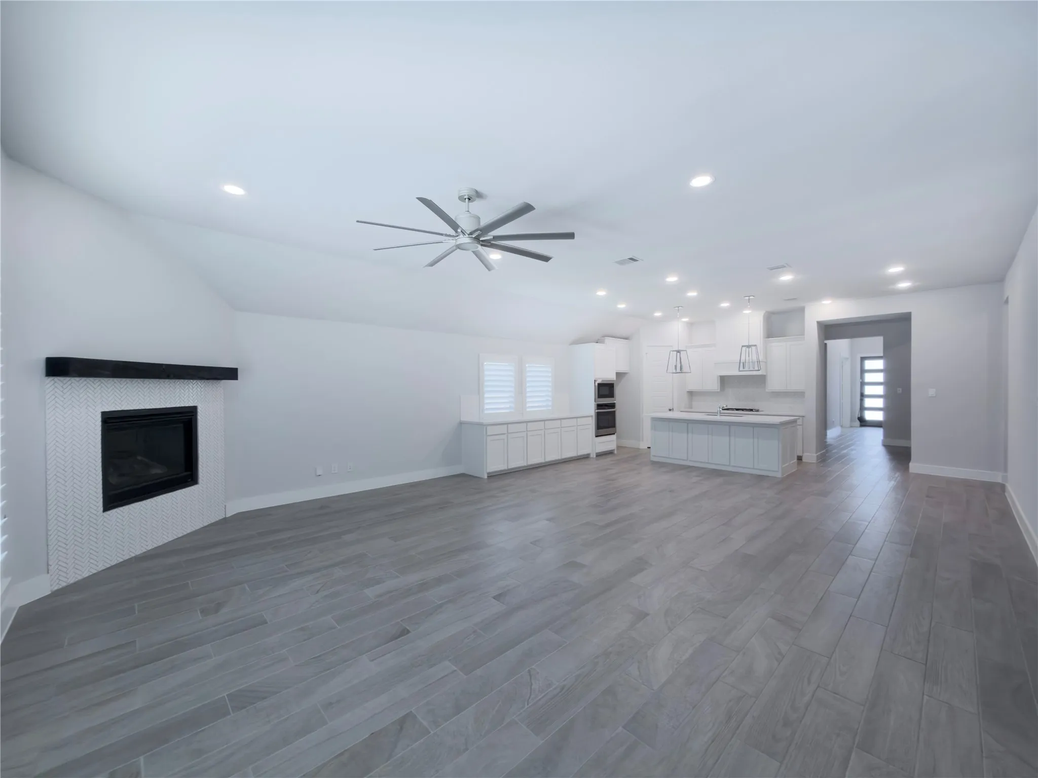Spacious common area featuring light wood-finish flooring, a contemporary ceiling fan, and recessed lighting