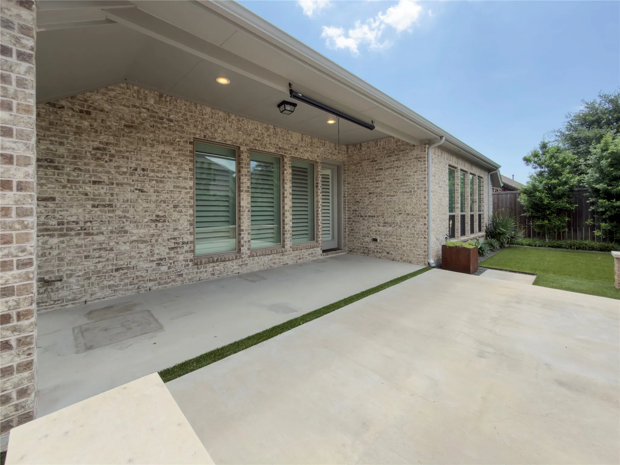 Expansive concrete patio area featuring integrated artificial turf accents