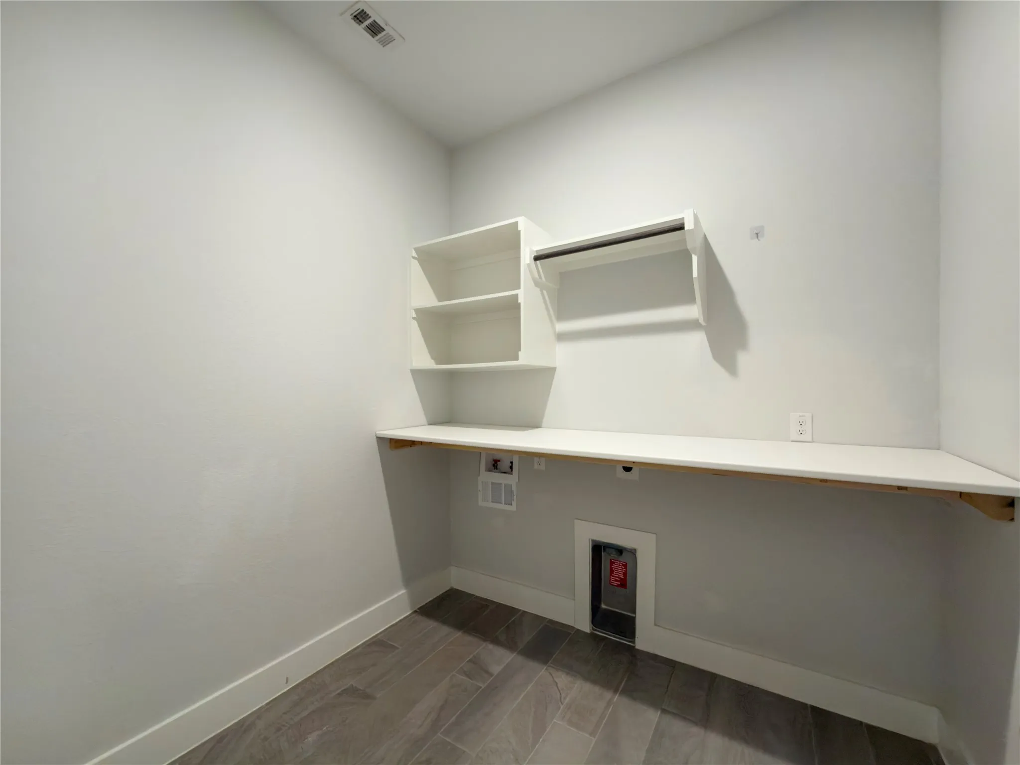 Dedicated utility room featuring built-in white shelving, a hanging rod, and a spacious counter