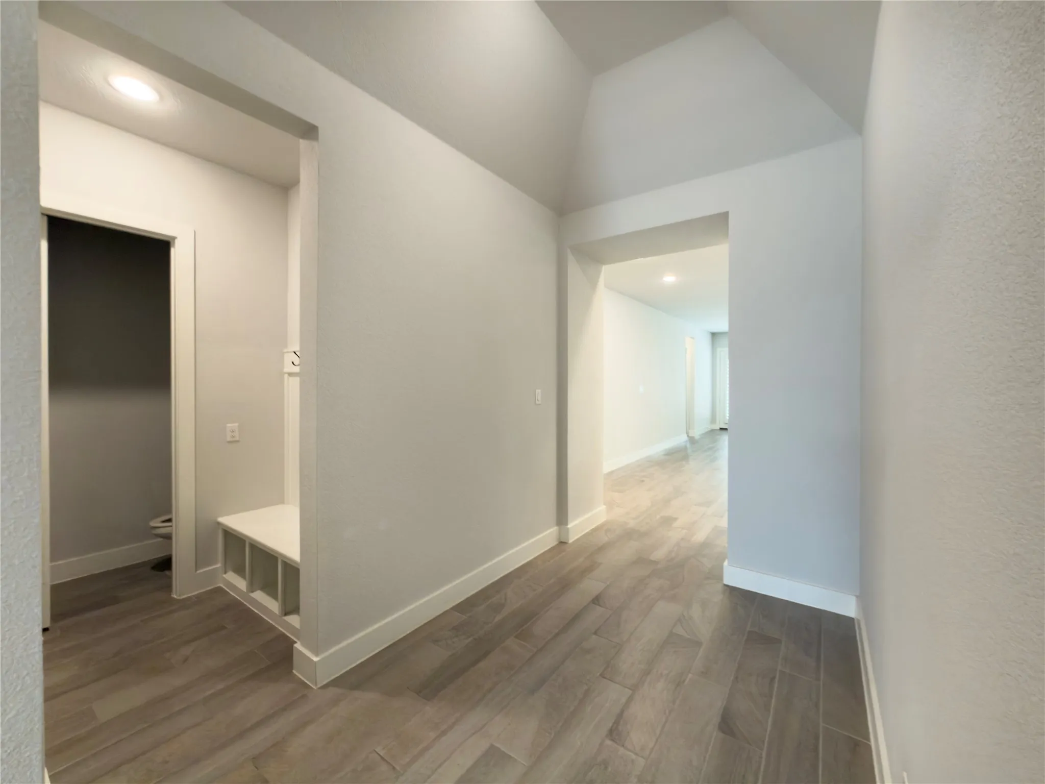 Entryway featuring wood-finish tile flooring, recessed lighting, and a built-in bench with storage cubbies