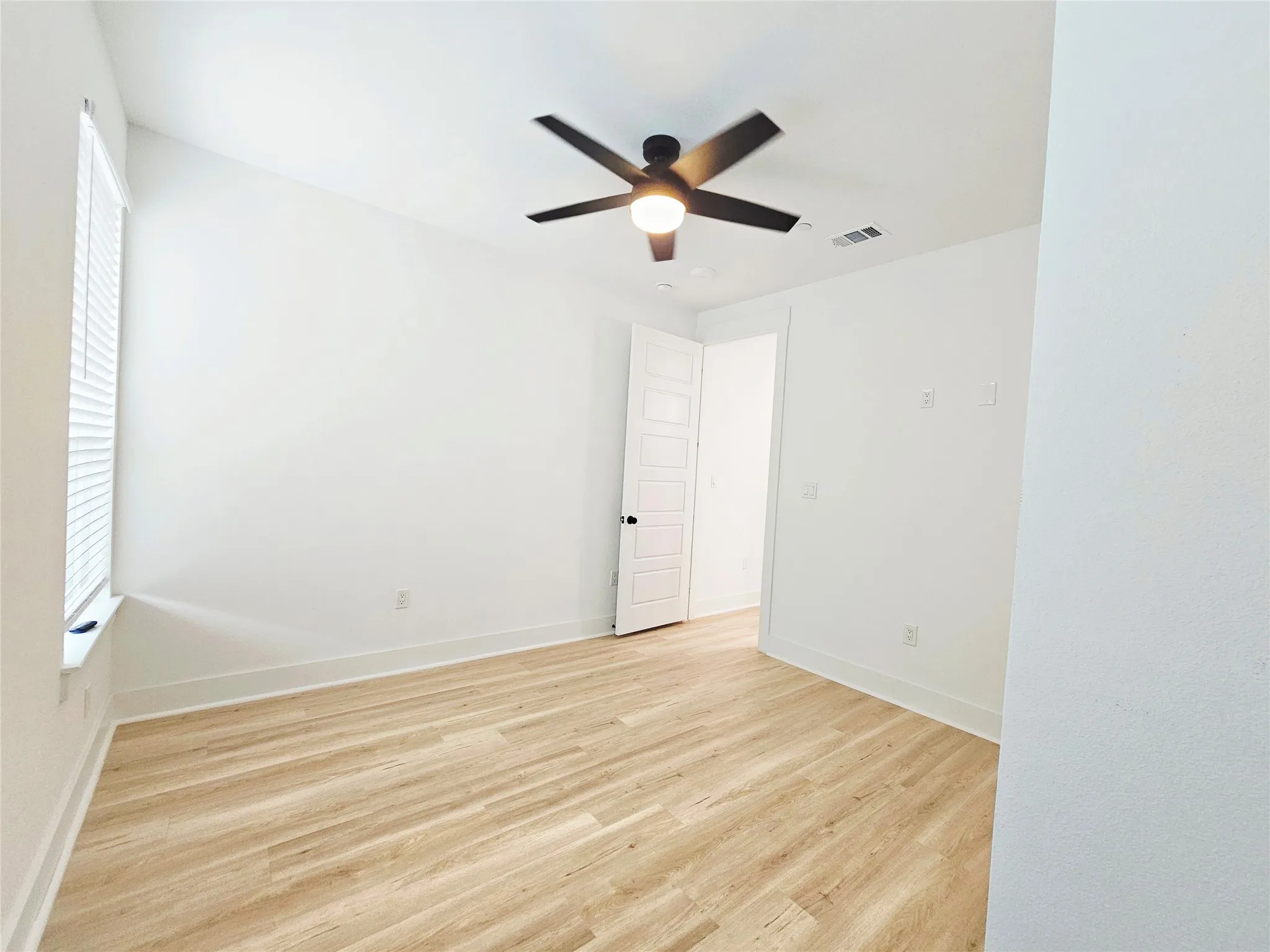 Unfurnished room with light wood-style floors, a ceiling fan, baseboards, and healthy amount of natural light