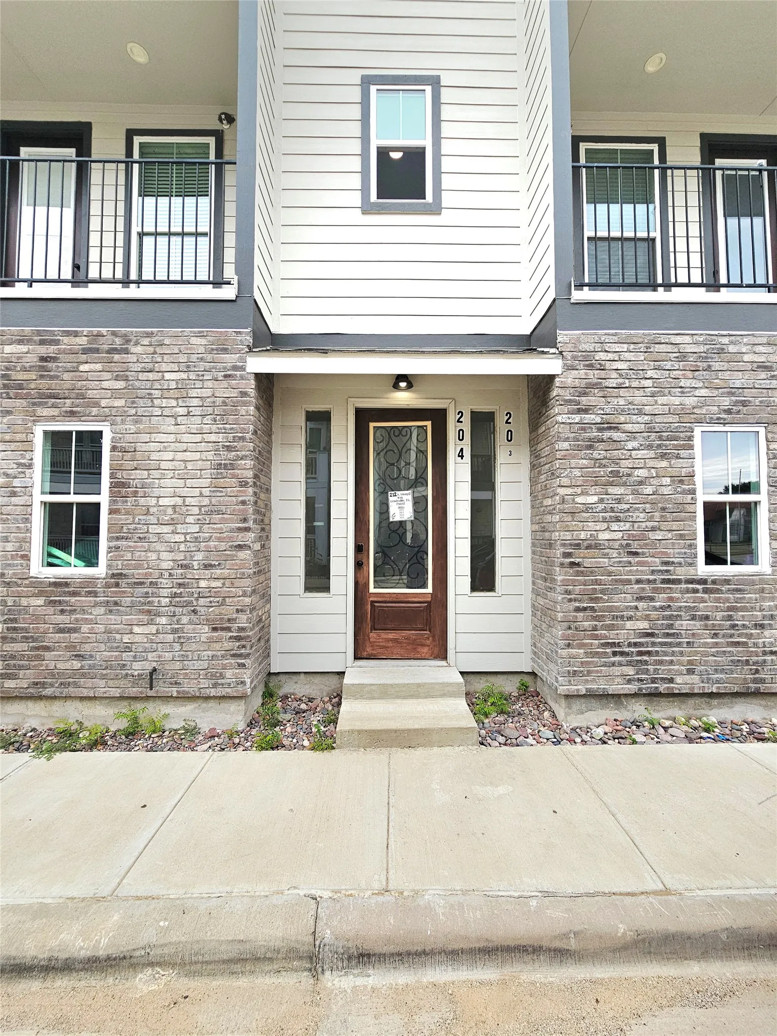 View of exterior entry featuring brick siding and a balcony