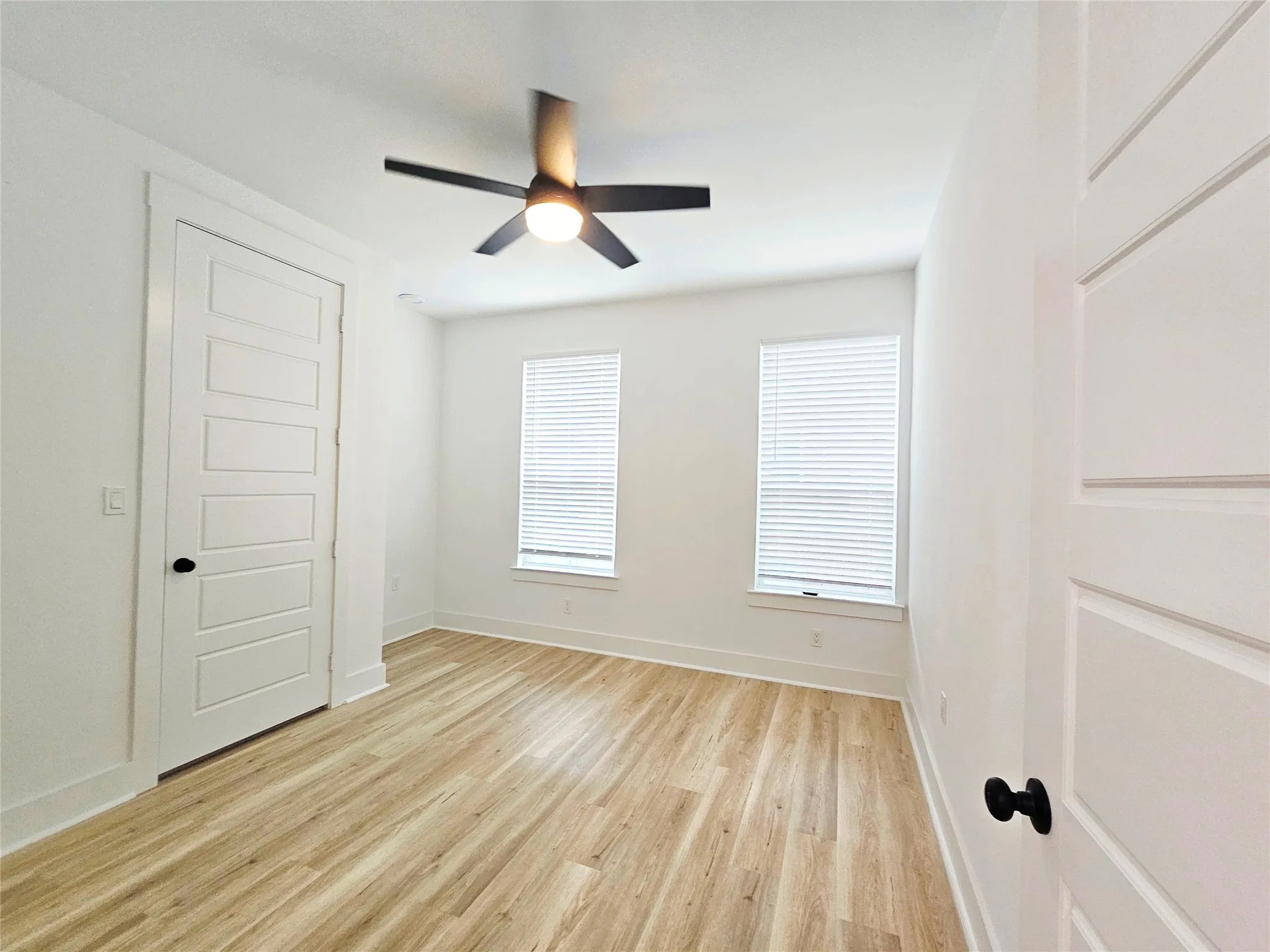 Empty room with light wood finished floors, a ceiling fan, and baseboards