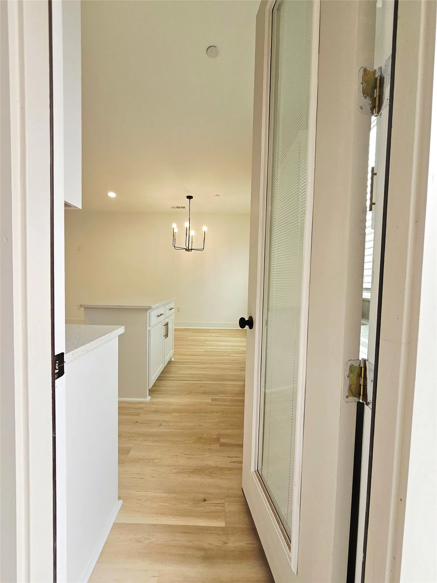 Corridor with light wood-style flooring, a chandelier, baseboards, and recessed lighting