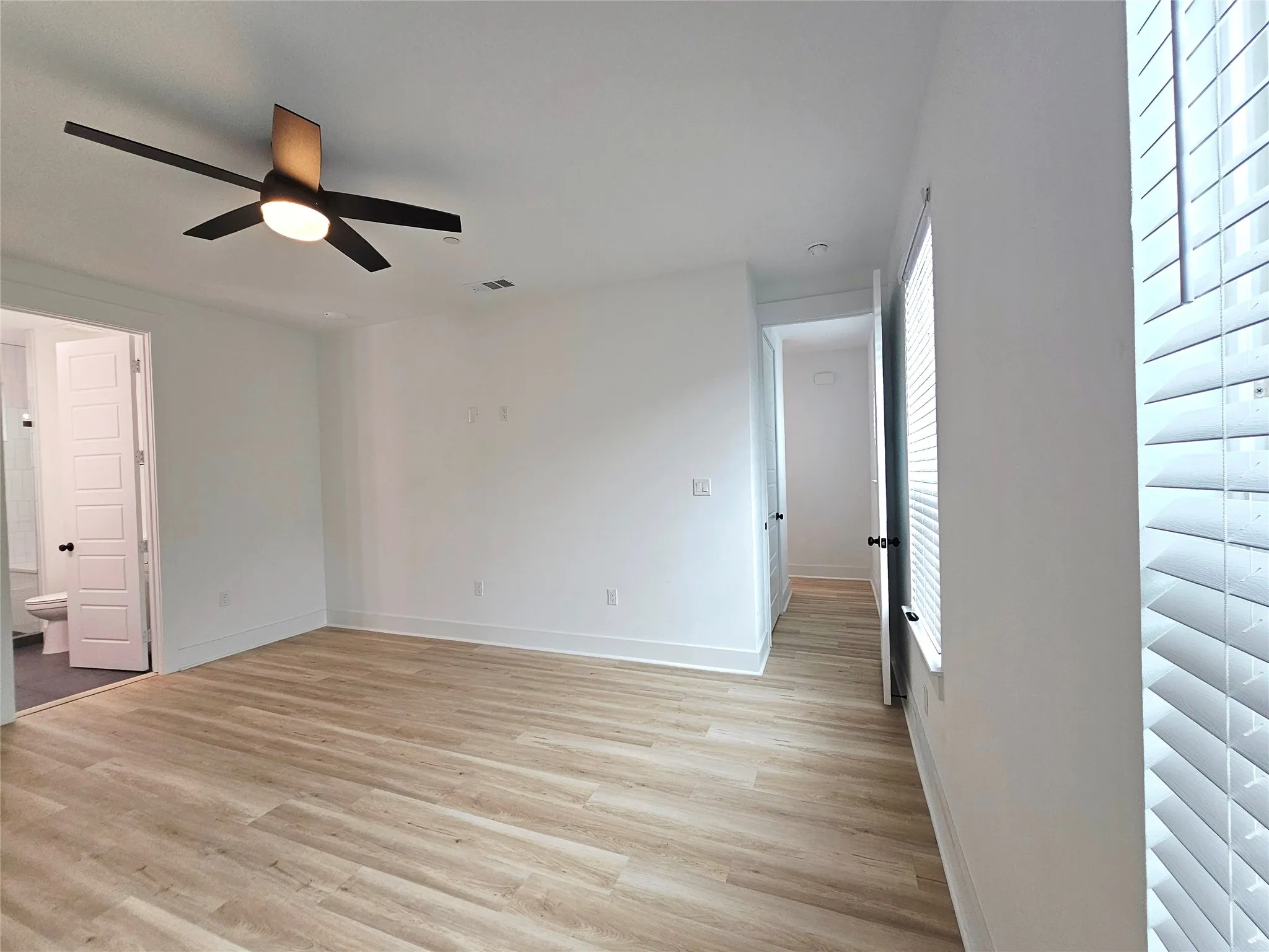 Spare room with a ceiling fan, plenty of natural light, light wood finished floors, and baseboards