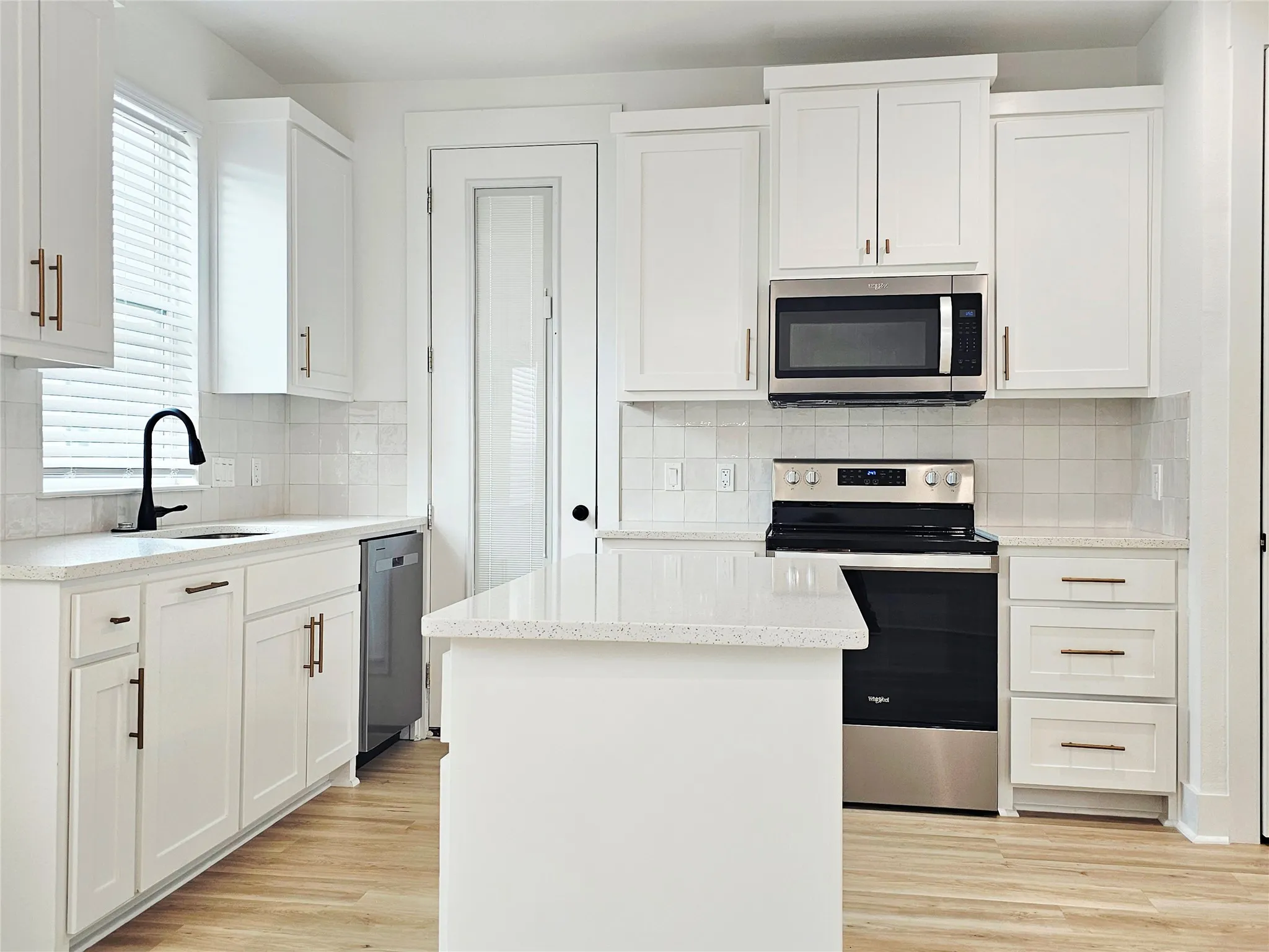 Kitchen with appliances with stainless steel finishes, a sink, light wood-style flooring, and white cabinetry