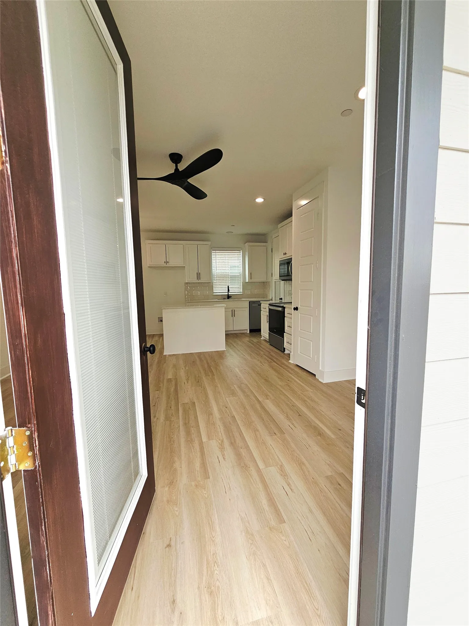 Unfurnished living room with ceiling fan, light wood-style flooring, a sink, recessed lighting, and baseboards