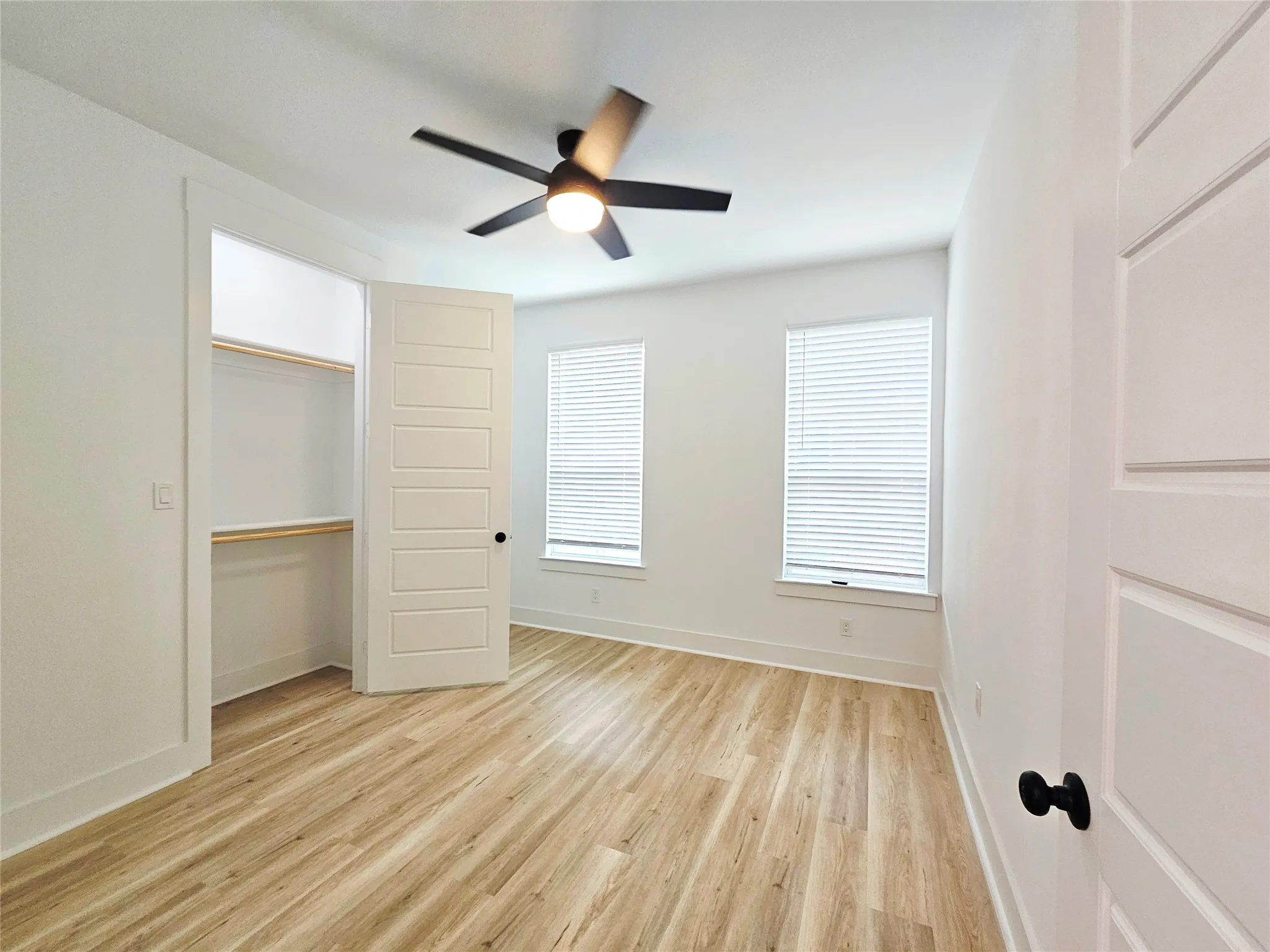 Unfurnished bedroom with light wood-type flooring, baseboards, a closet, and a ceiling fan