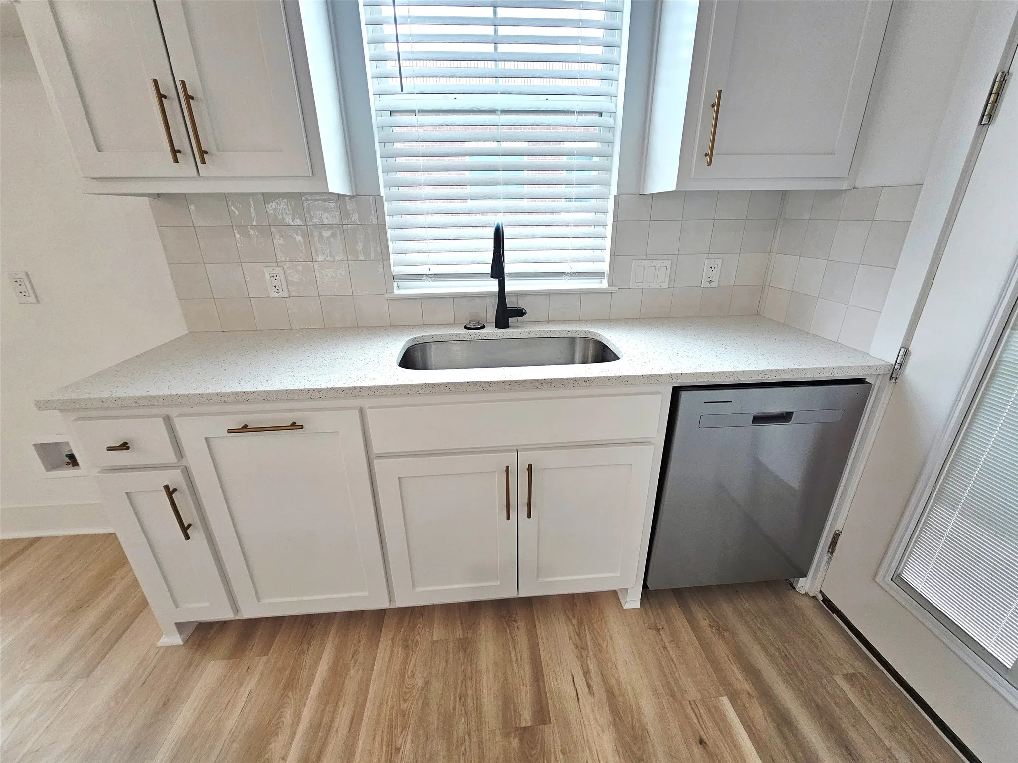 Kitchen featuring a sink, dishwasher, light wood-style flooring, and white cabinets