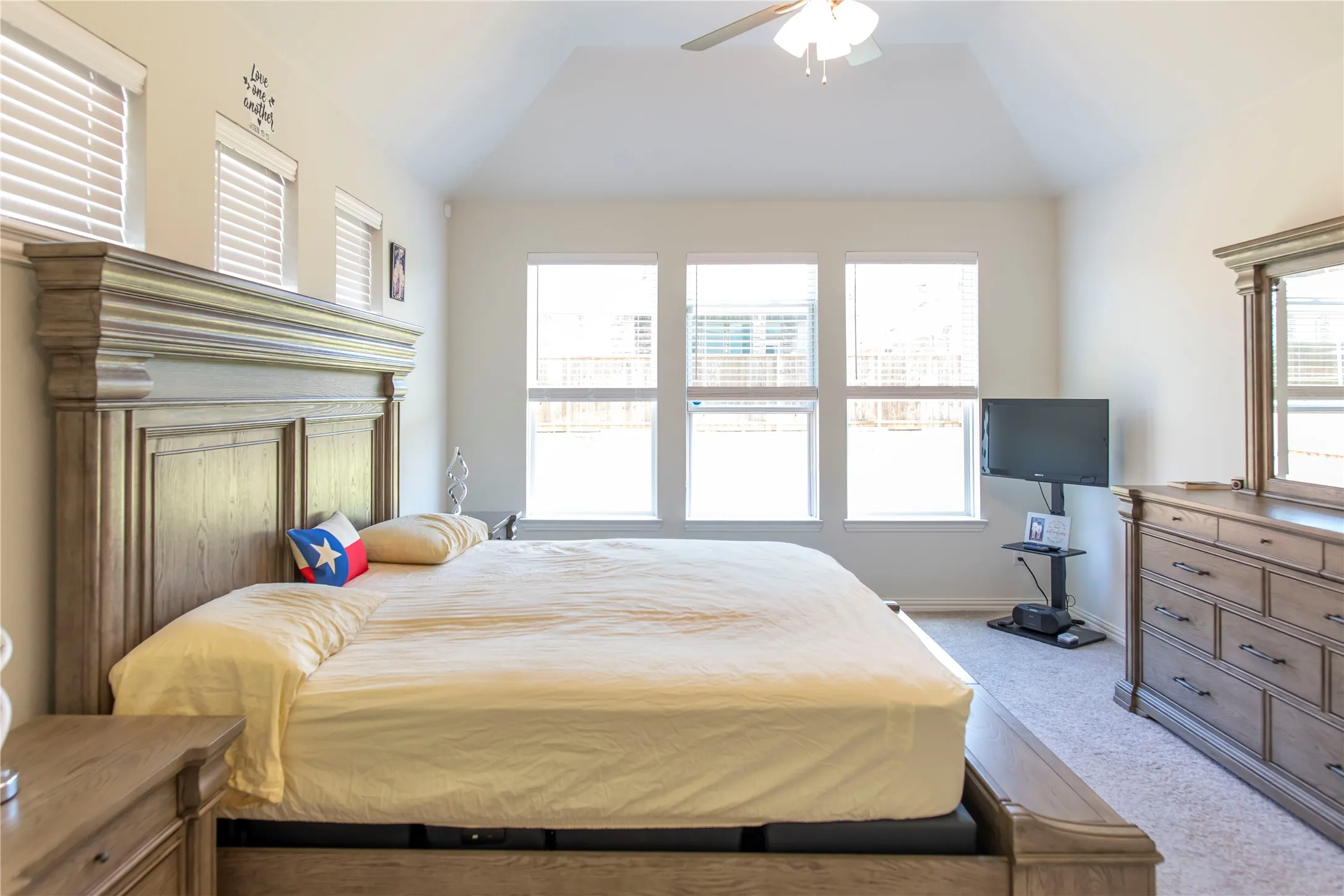 Vaulted ceiling room featuring multiple windows, neutral wall tones, and carpeted flooring