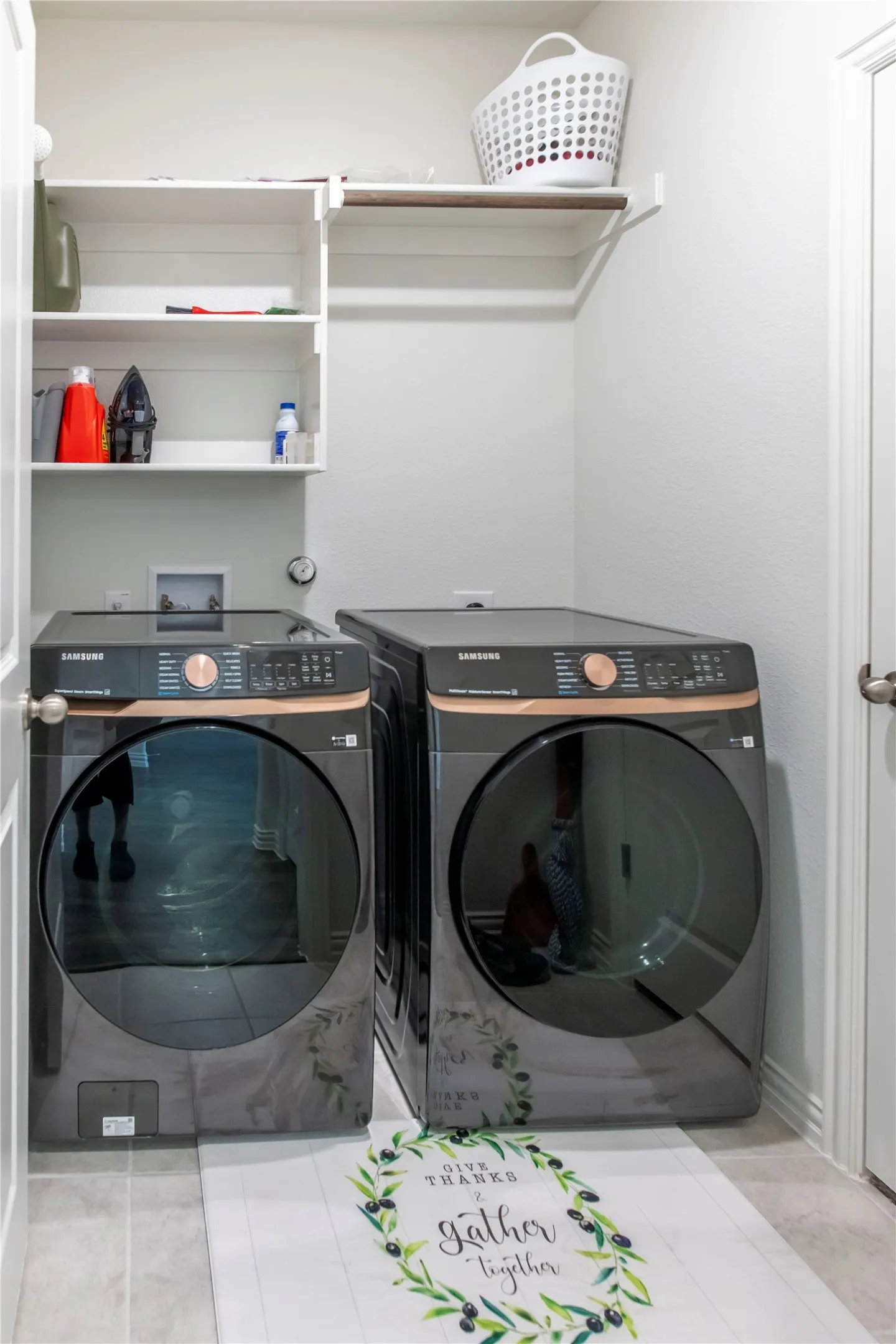 Dedicated laundry area featuring a built-in shelving unit, overhead hanging rod, and tile flooring