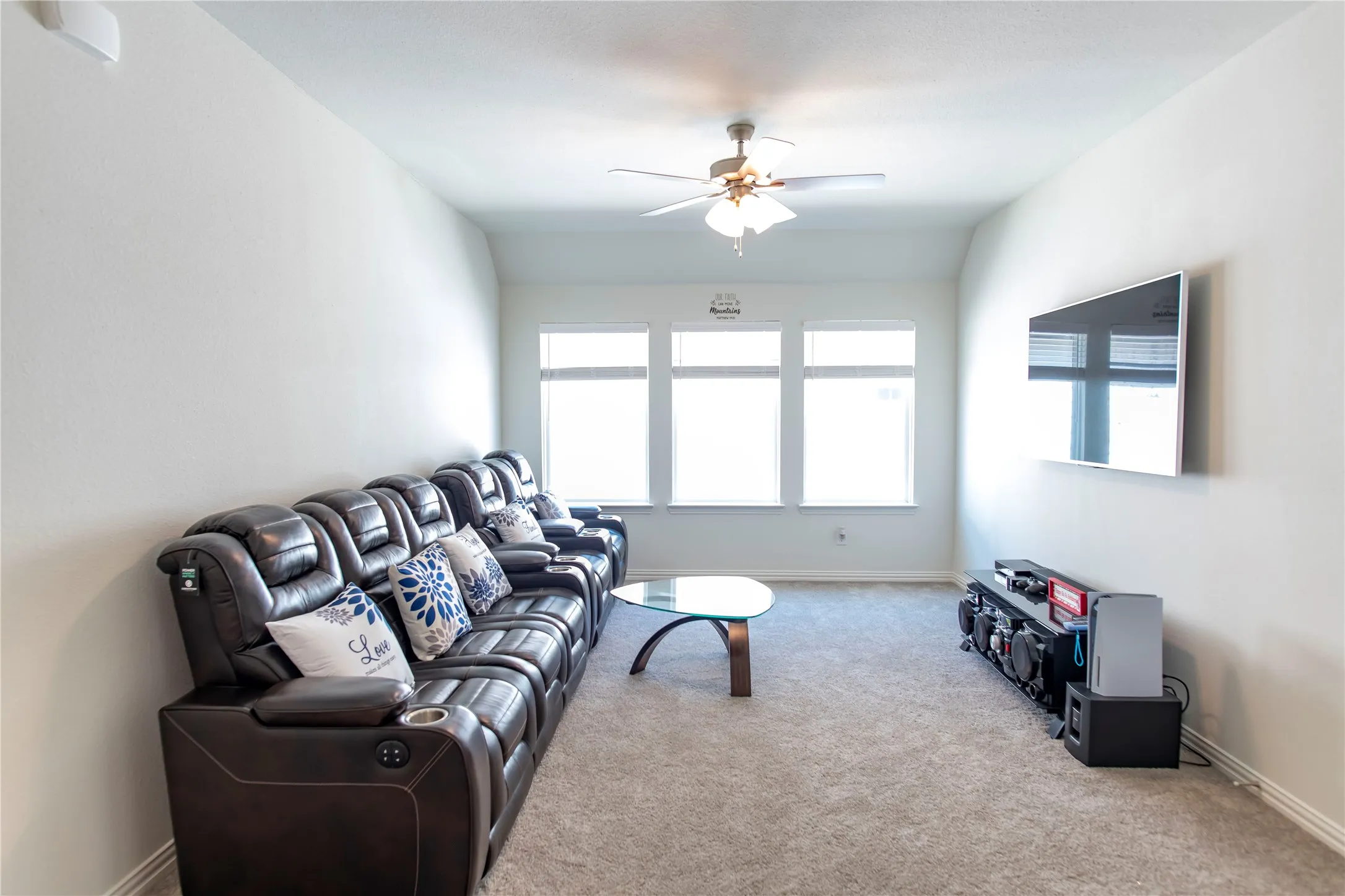 Carpeted living space featuring light-colored walls and a vaulted ceiling