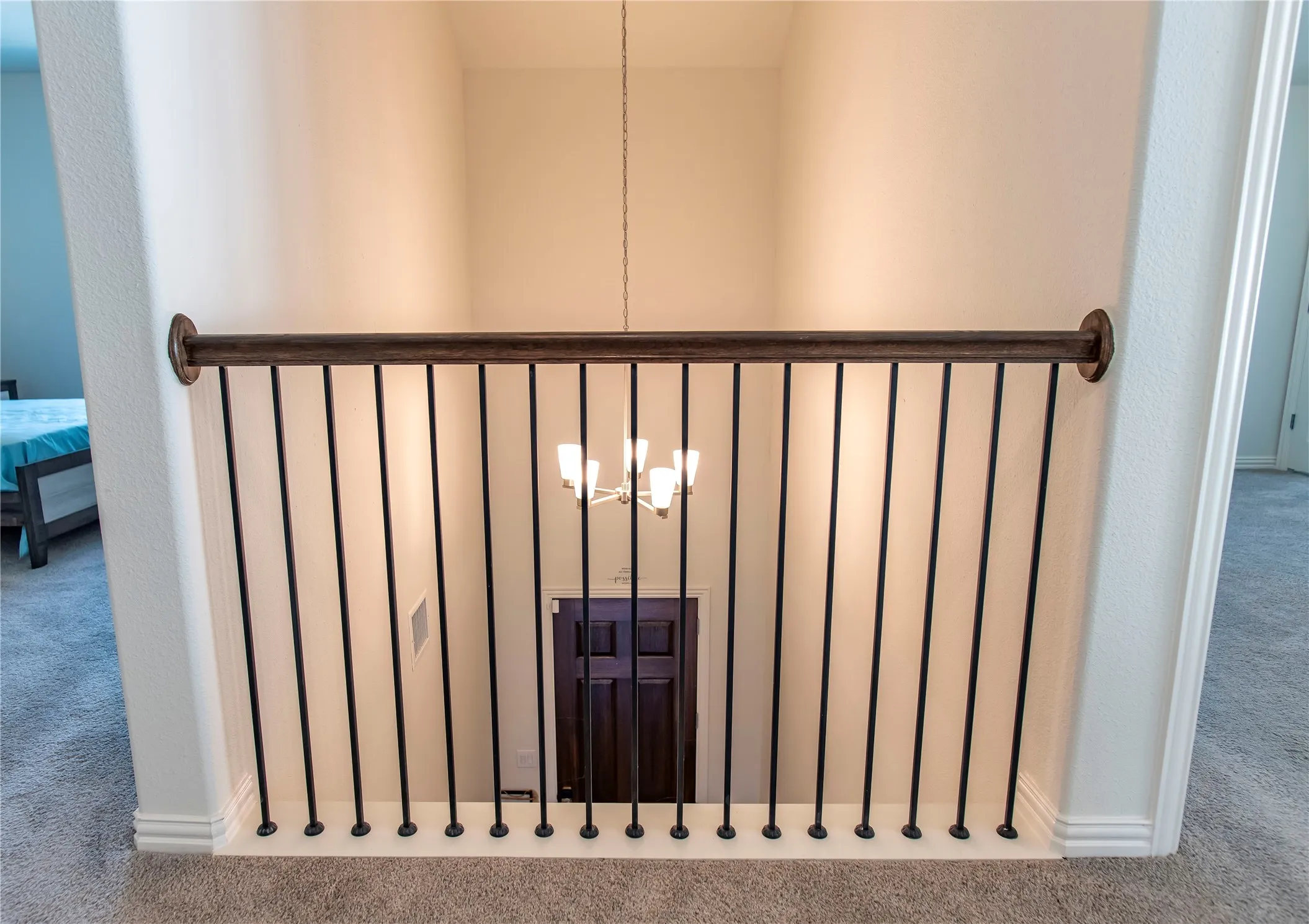 Wrought iron-style balusters with a dark wood-finish handrail, light neutral wall tones, and plush carpet flooring throughout