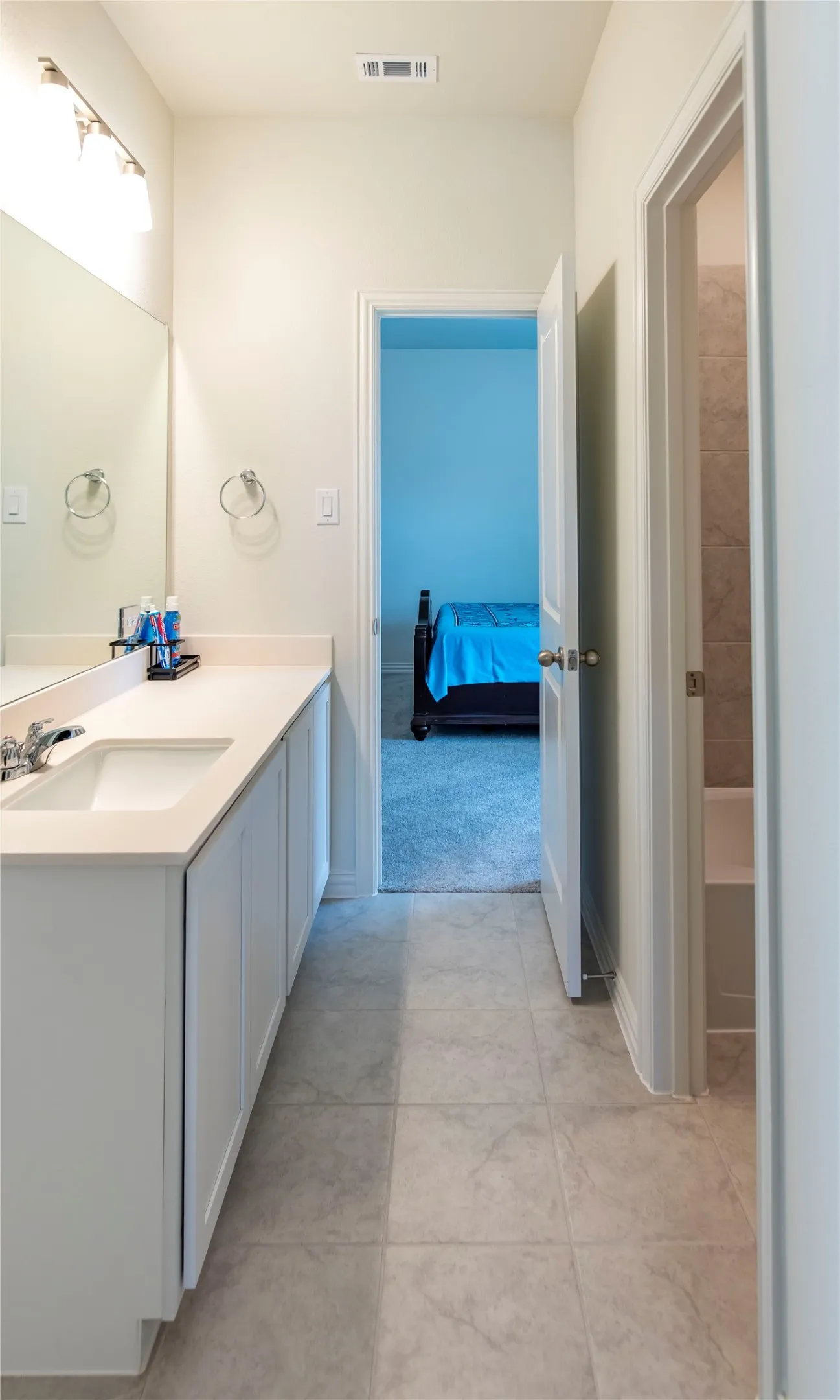 Bathroom vanity with a white countertop and integrated sink, chrome faucet, and mirrored wall