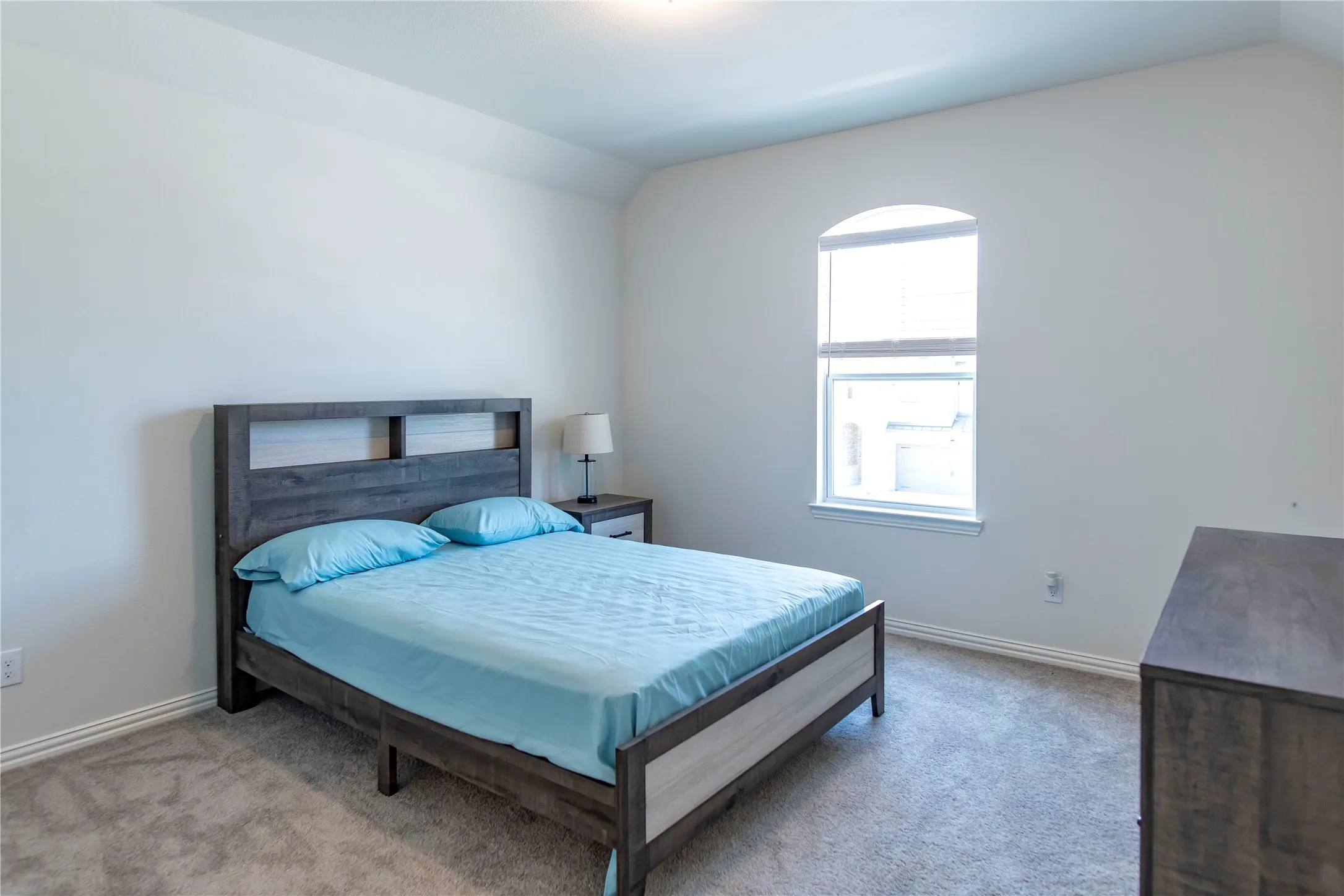 Carpeted room featuring a single arched window, white baseboards, and neutral wall paint