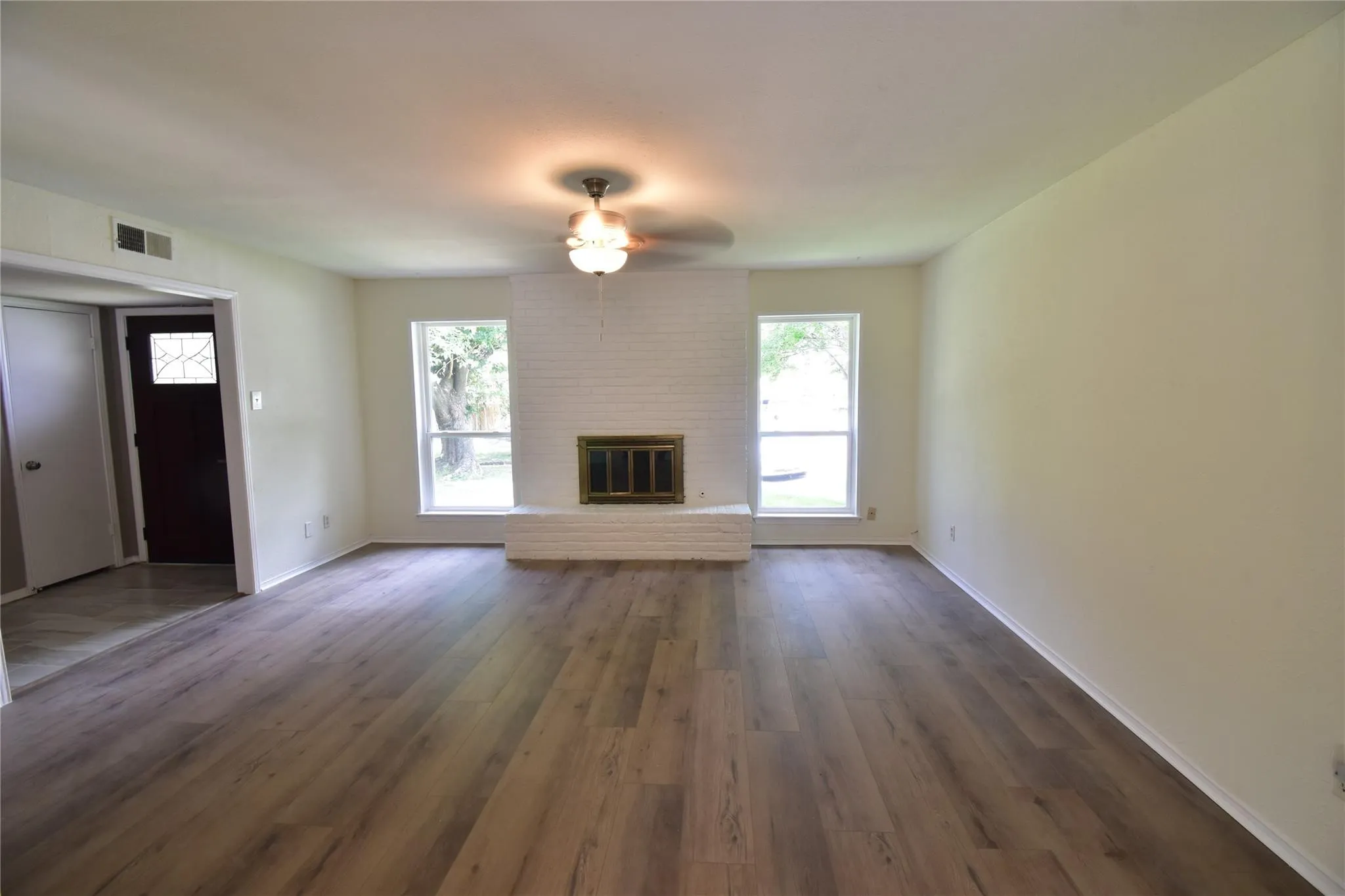 Large living room with clean ceiling, elegant wood floor, ceiling fan and plenty of natural  light