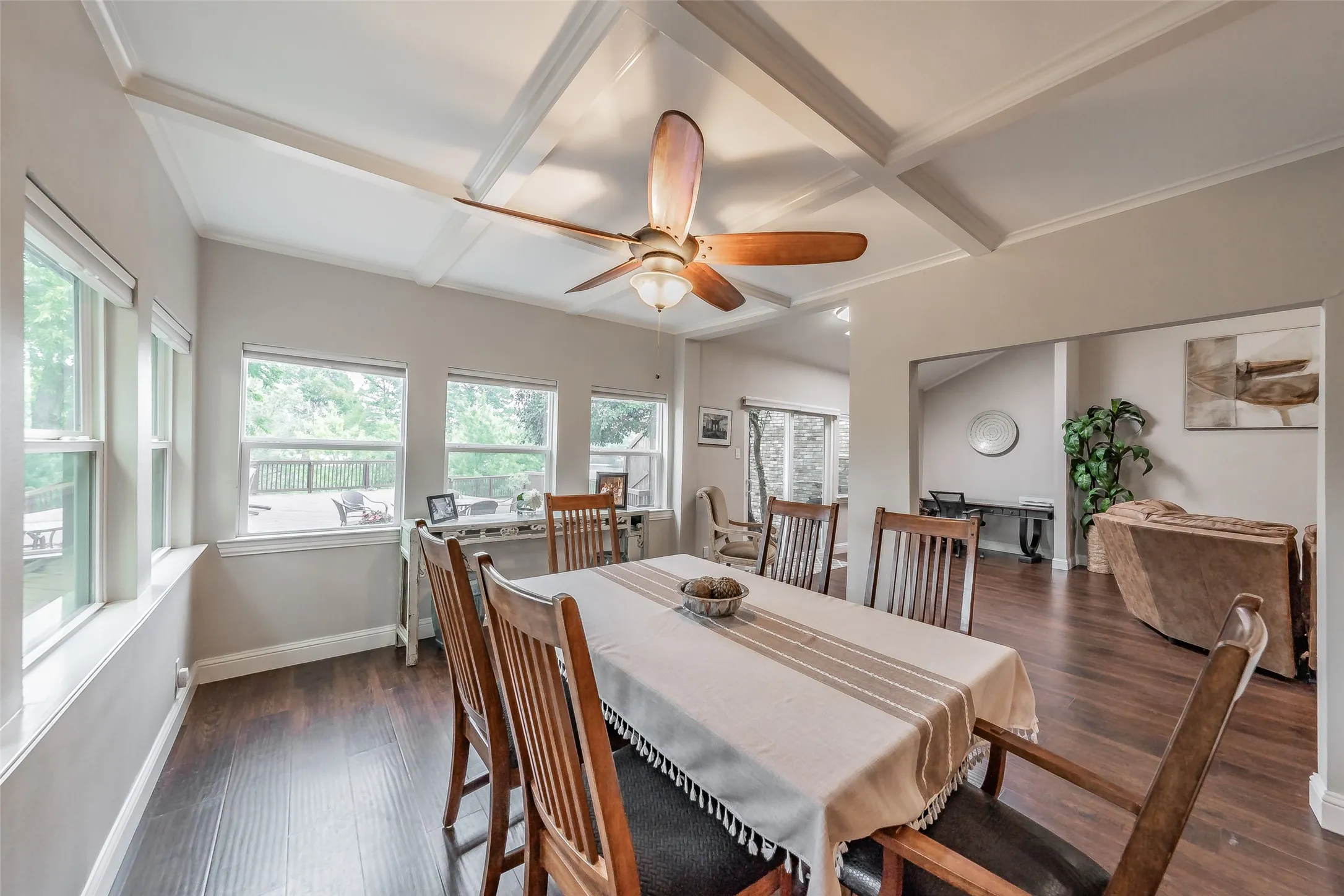 Dining area featuring wood-finish flooring, a coffered ceiling, a ceiling fan with integrated lighting, and multiple windows